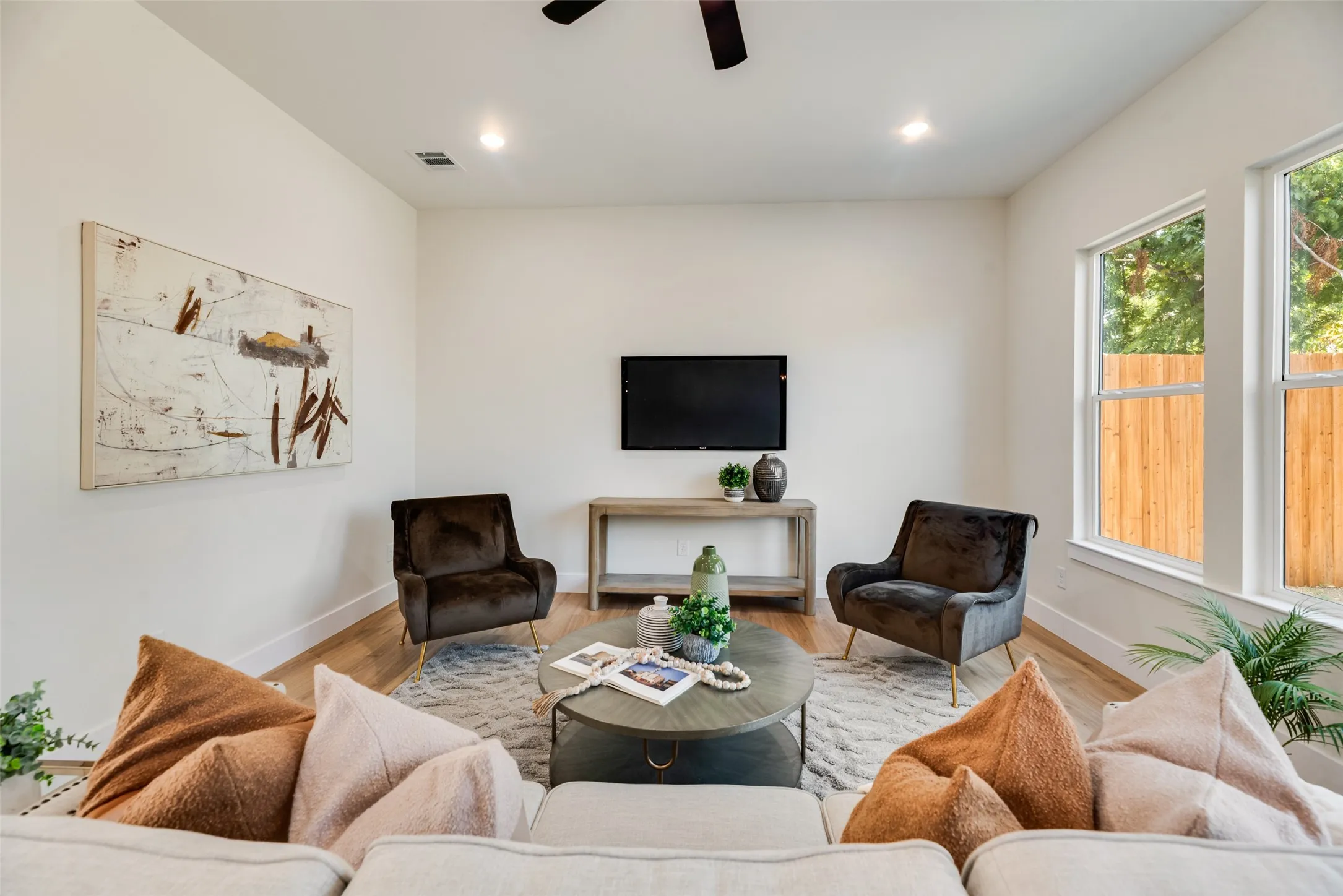 Recessed lighting, wood-finish flooring, white walls, multiple windows, and a ceiling fan