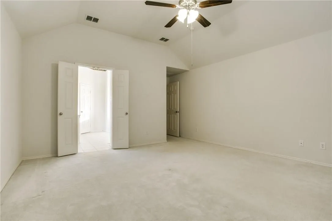 Unfurnished bedroom with ceiling fan, vaulted ceiling, and light colored carpet