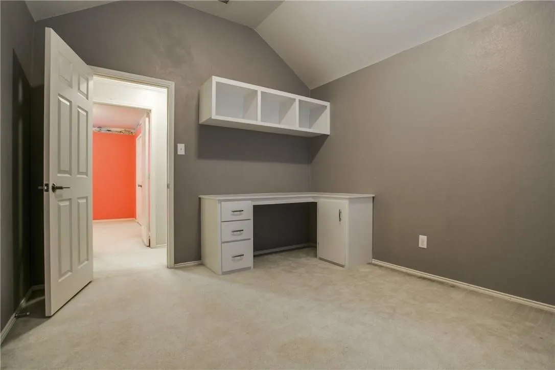 Unfurnished office featuring light carpet and vaulted ceiling