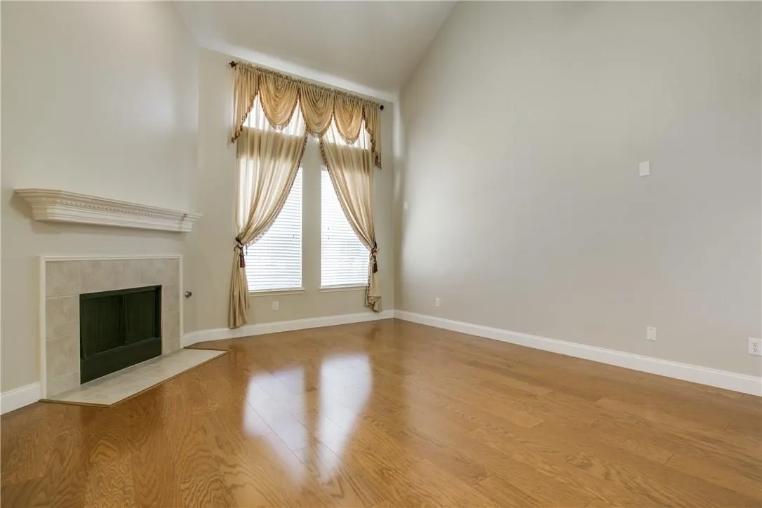 Unfurnished living room with light hardwood / wood-style floors, a tiled fireplace, and lofted ceiling