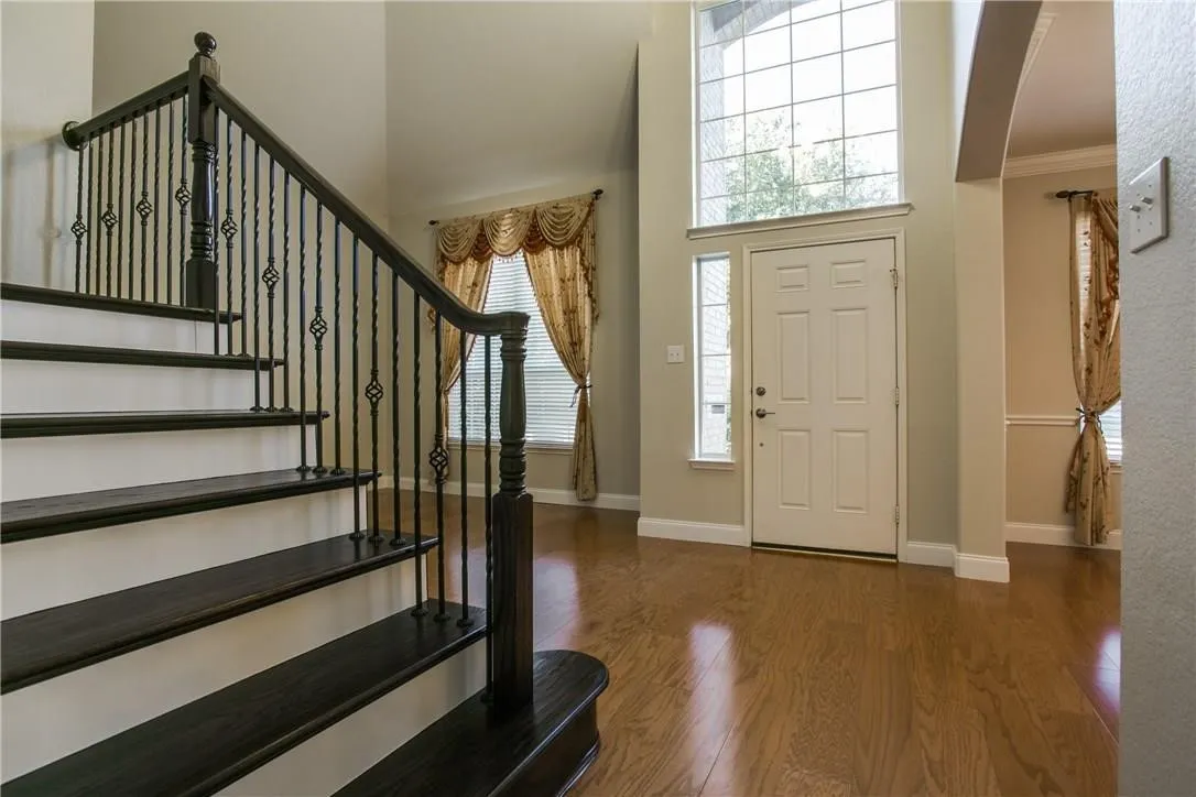 Entrance foyer with a high ceiling, dark wood-type flooring, ornamental molding, and a wealth of natural light