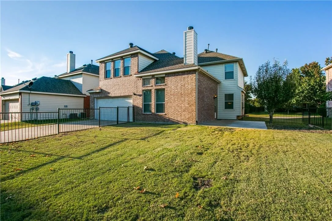 Back of house with a garage, a patio area, and a lawn