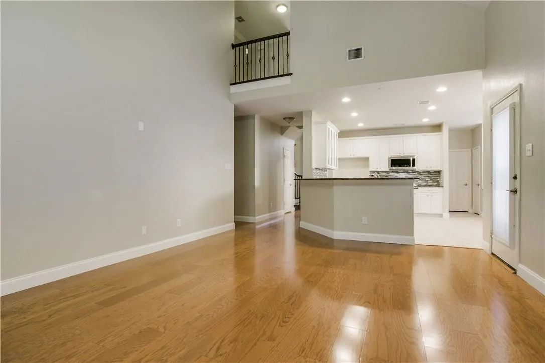 Unfurnished living room featuring light hardwood / wood-style flooring and a towering ceiling
