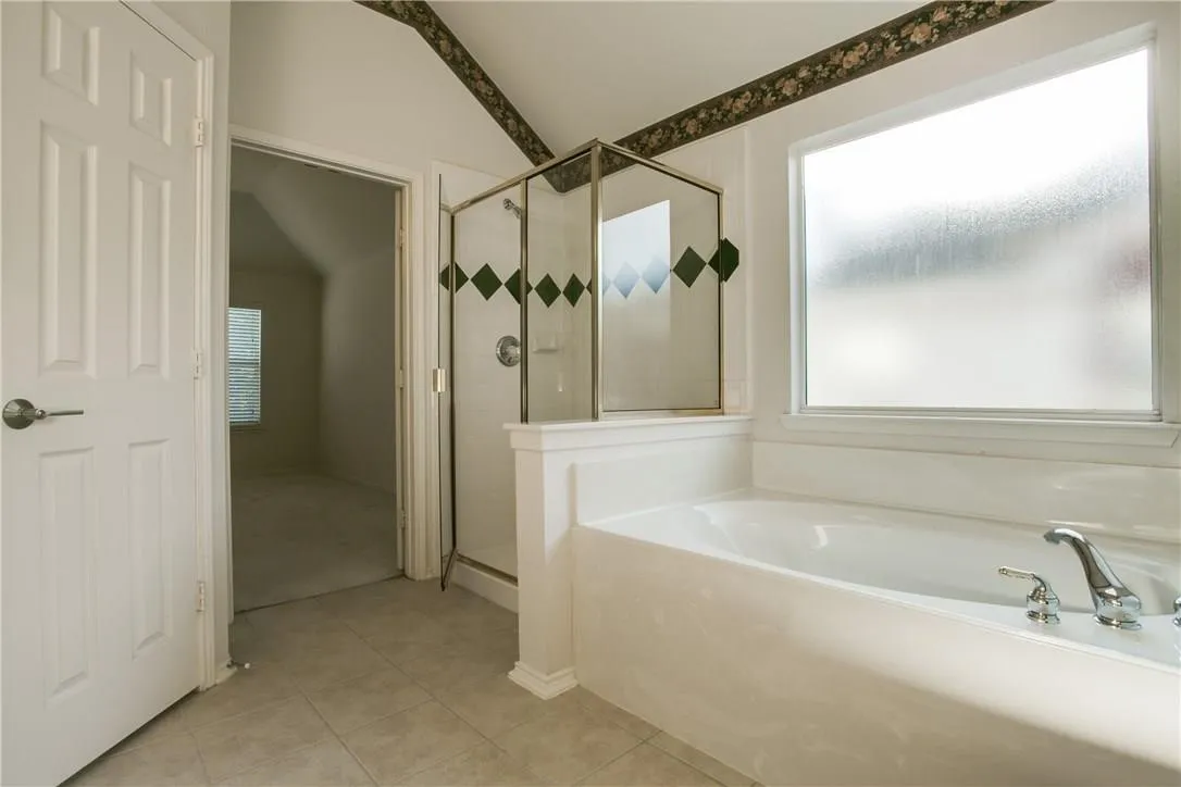 Bathroom featuring independent shower and bath, a wealth of natural light, and tile patterned flooring