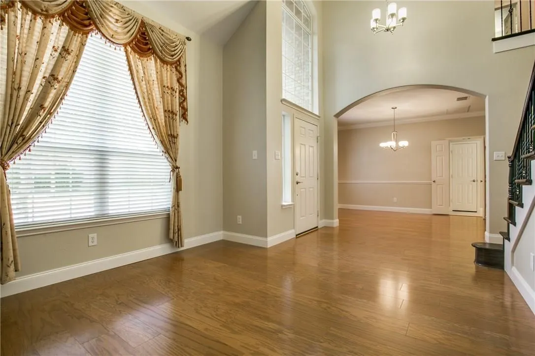 Entryway with ornamental molding, an inviting chandelier, wood-type flooring, and a high ceiling