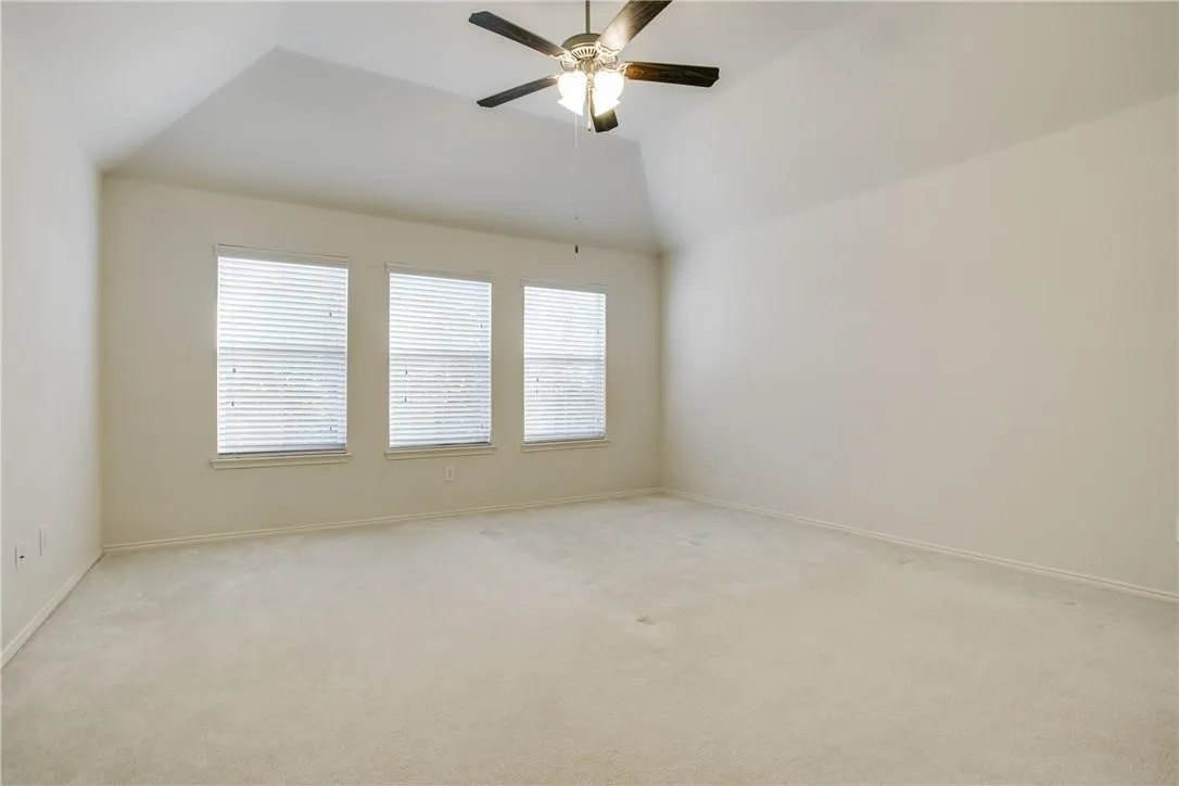 Spare room featuring lofted ceiling, carpet, and ceiling fan