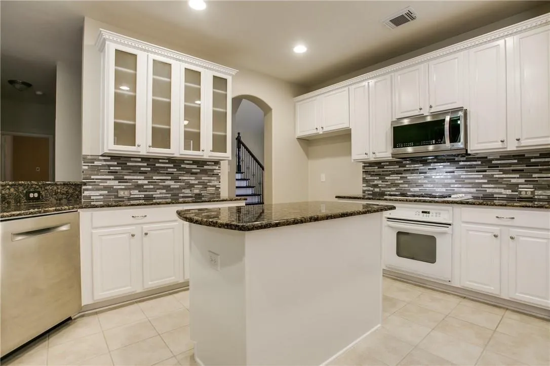 Kitchen with a kitchen island, appliances with stainless steel finishes, white cabinets, and backsplash
