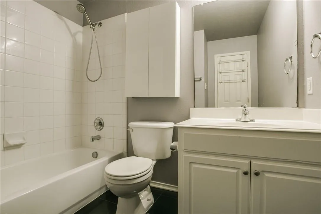 Full bathroom with vanity, tile patterned flooring, tiled shower / bath, and toilet