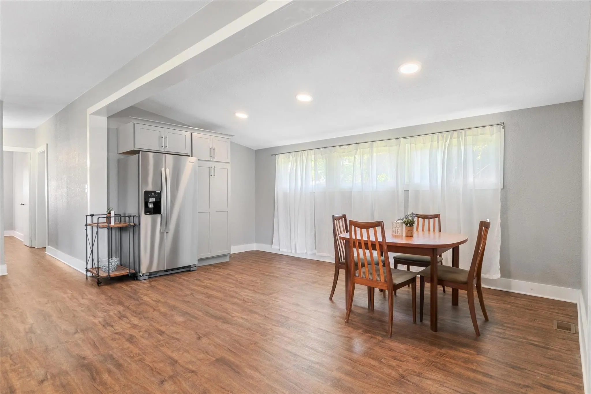 Recessed ceiling lighting, wood-finish flooring, white trim, and a wide window opening