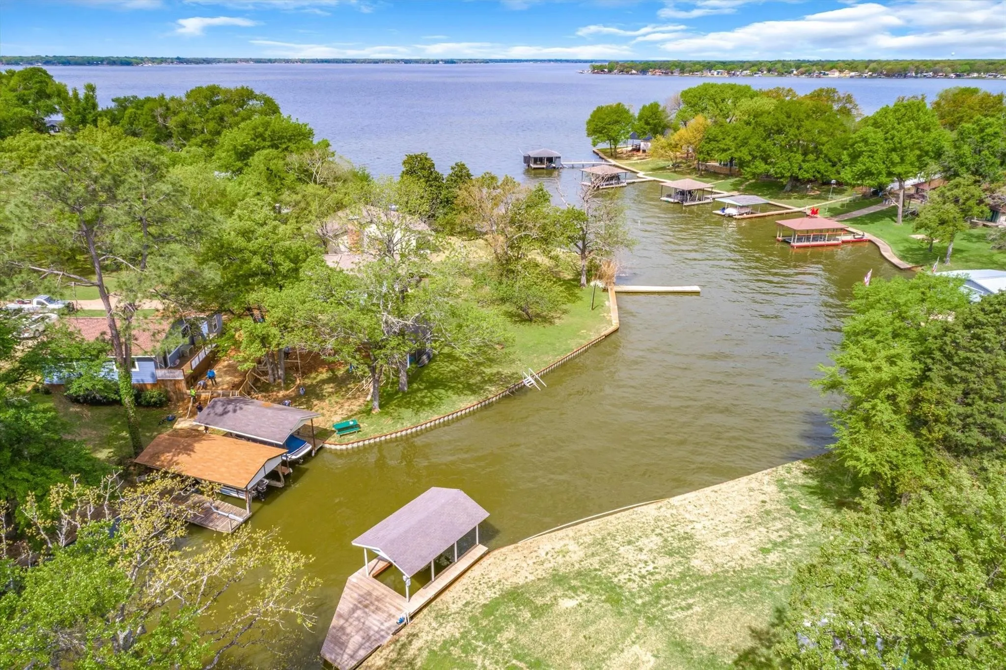 Waterfront property featuring a private boat dock with a covered slip, direct access to a spacious lake, and mature trees