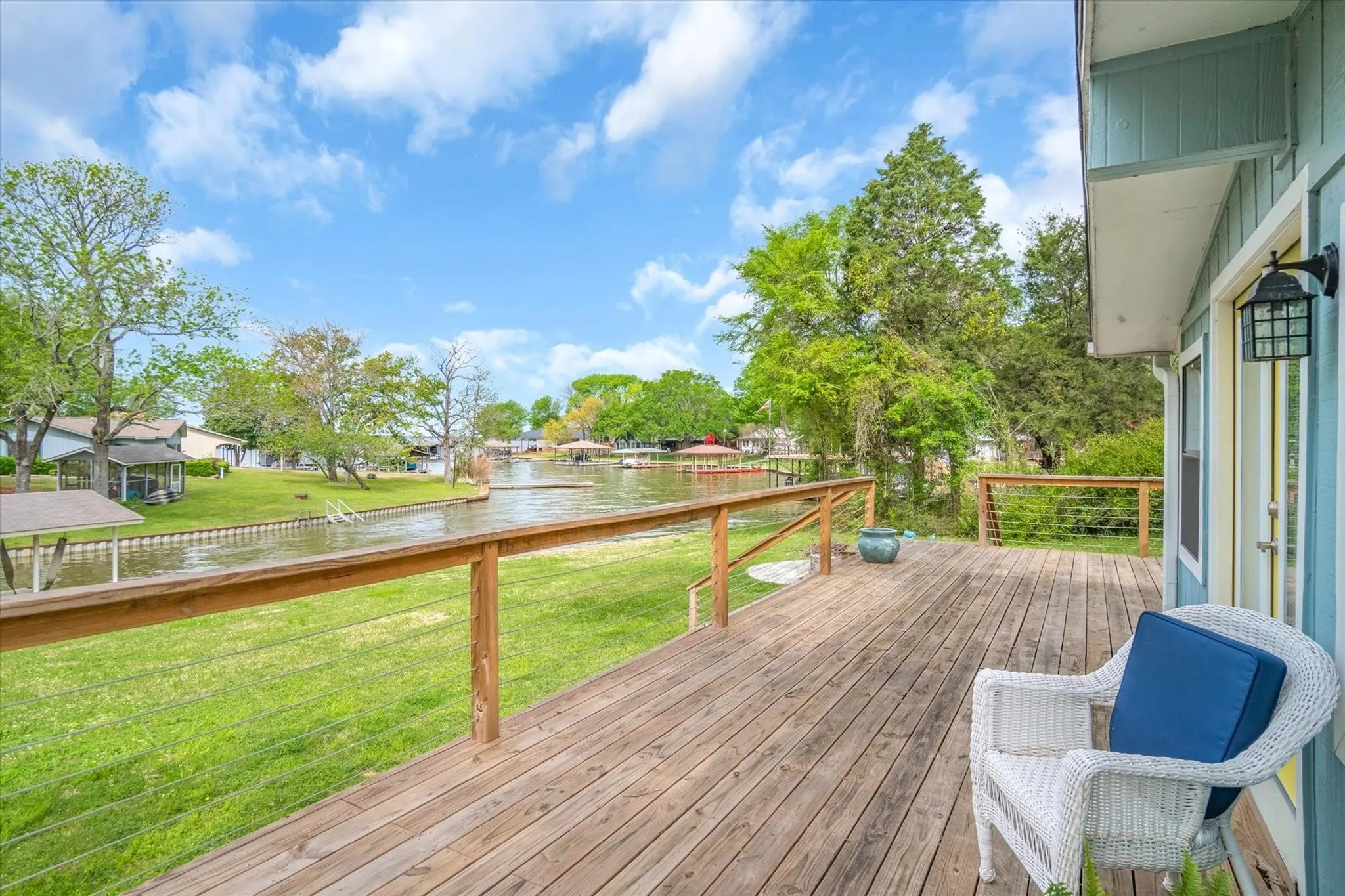 Expansive wood deck with cable railing overlooking a canal