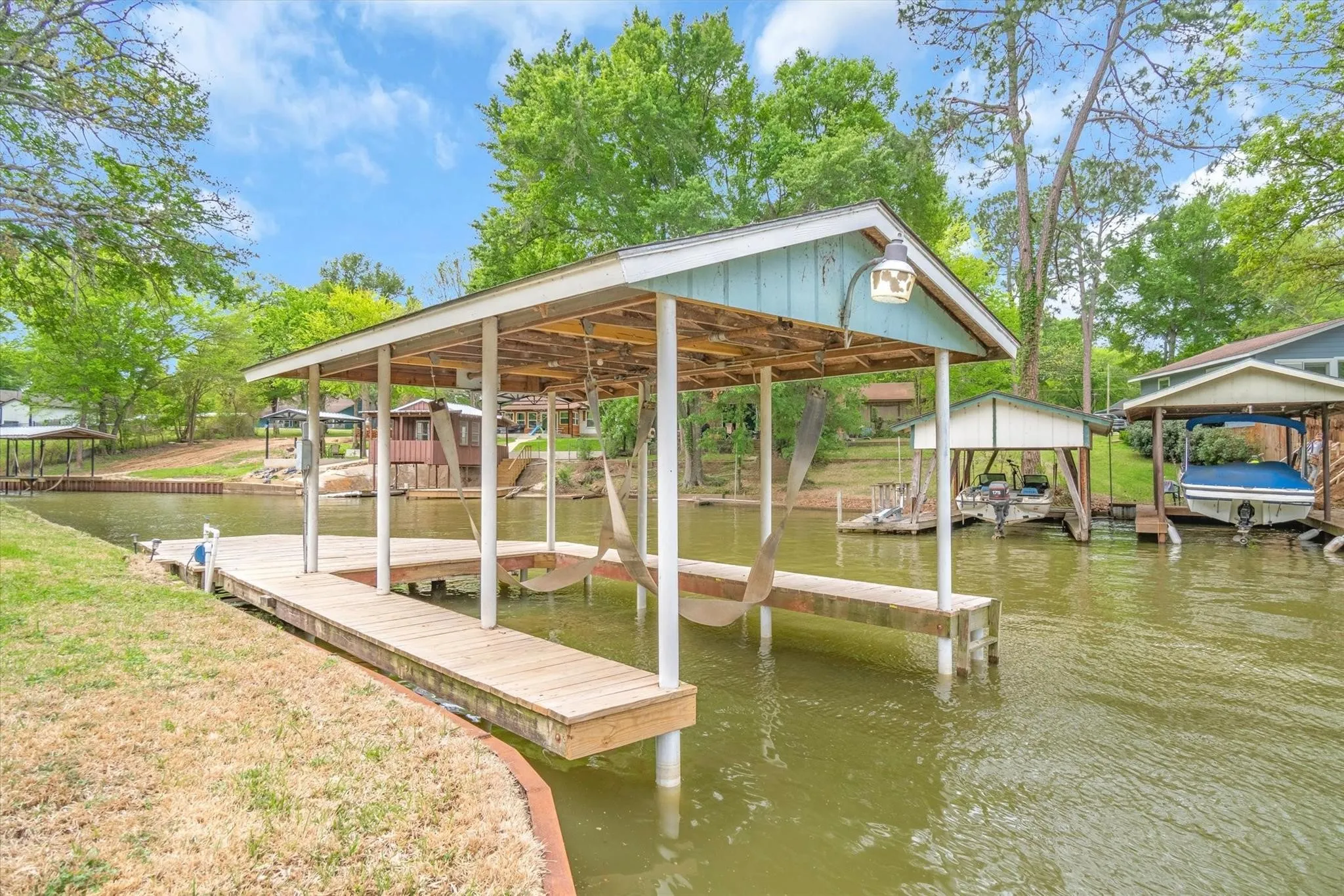 Covered boat dock featuring a wood-finish walkway and a built-in light fixture