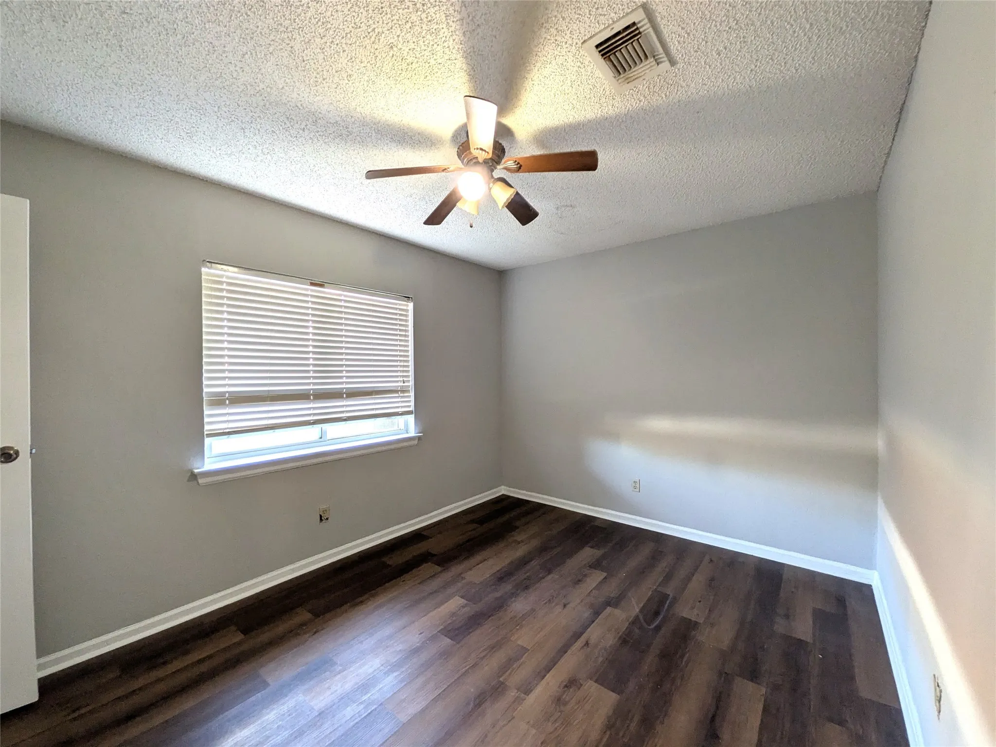 Wood-finish flooring, ceiling fan with integrated lighting, and window with blinds