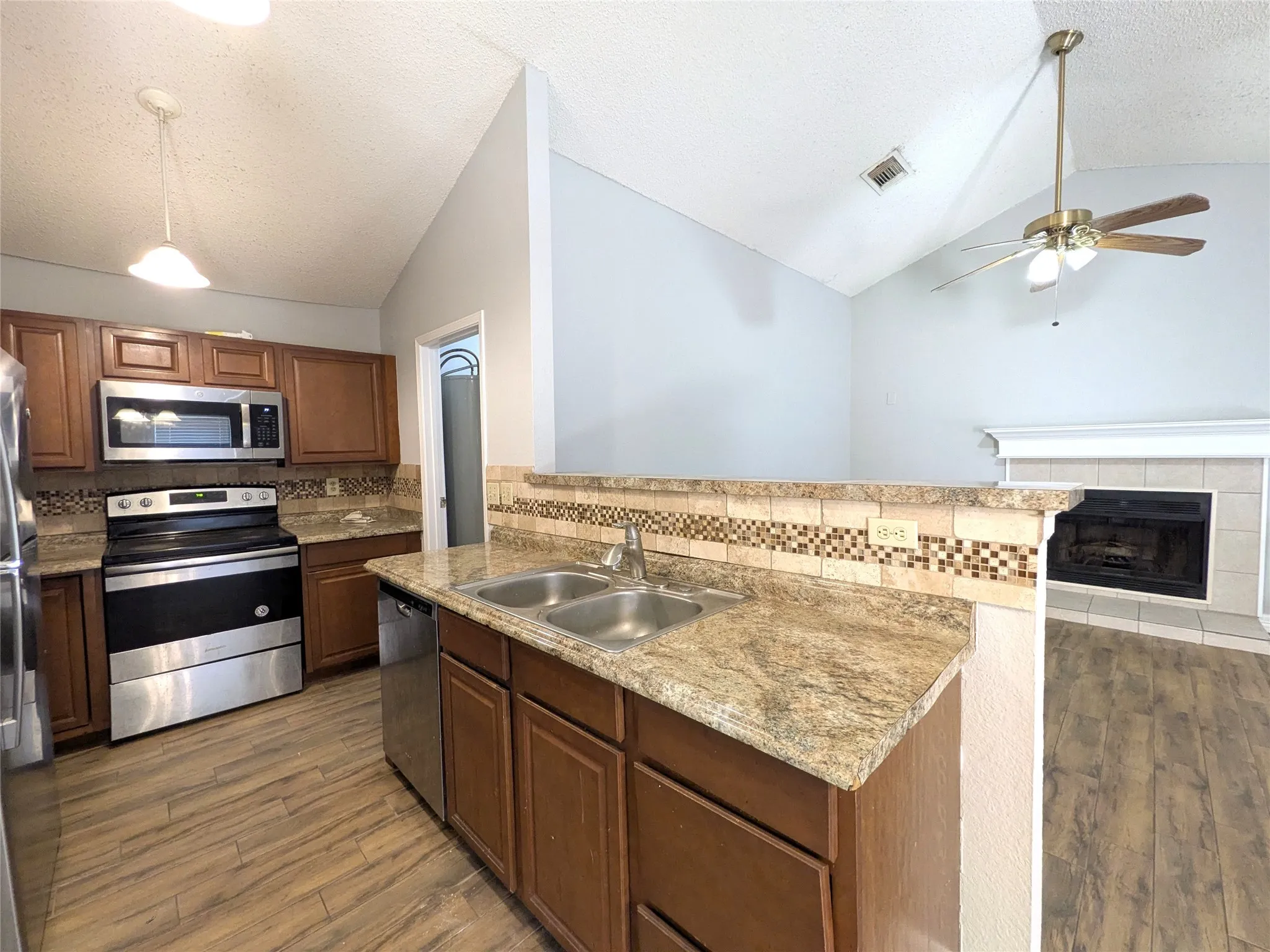 Kitchen featuring wood-finish flooring, stainless steel appliances, and a double basin sink