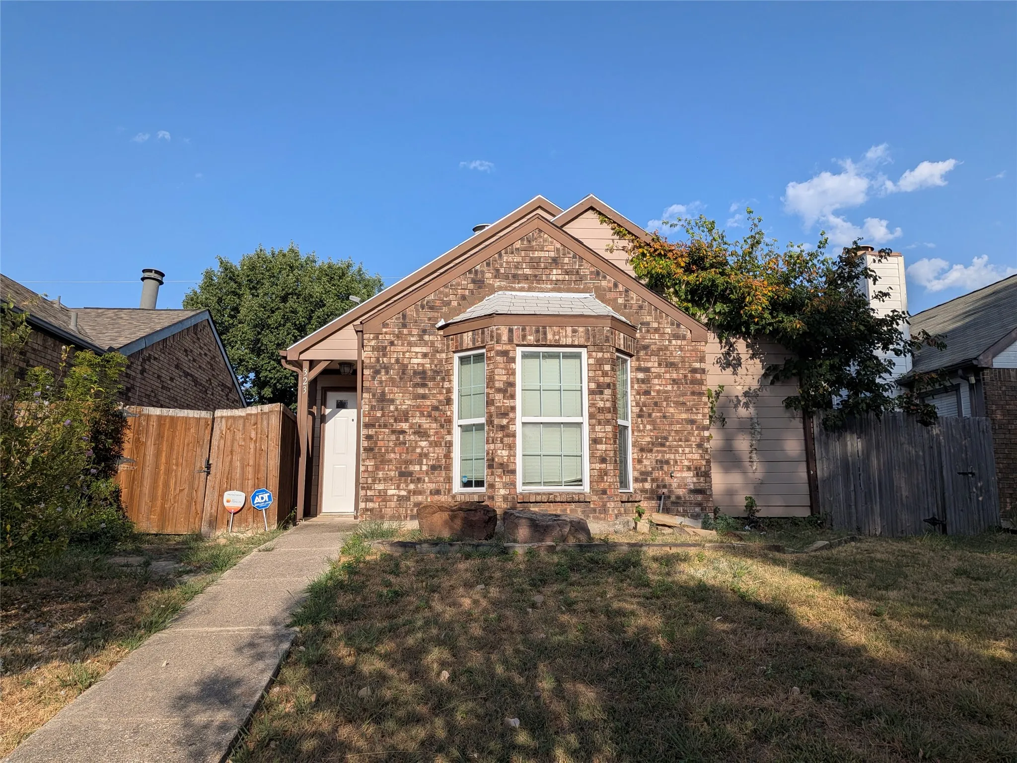 Brick exterior with a bay window, covered entry, and a concrete pathway