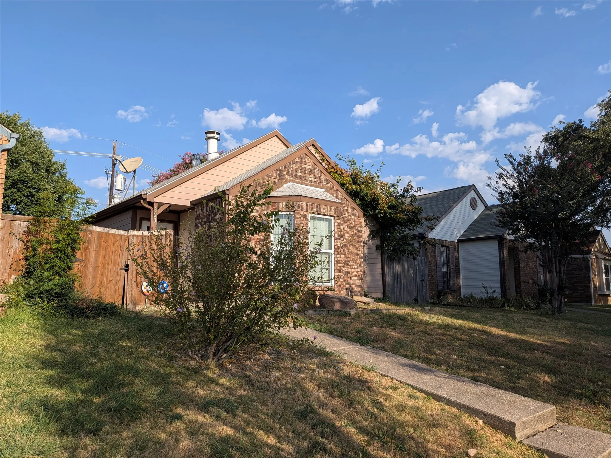 Brick exterior with a peaked roofline, bay window, and a concrete pathway