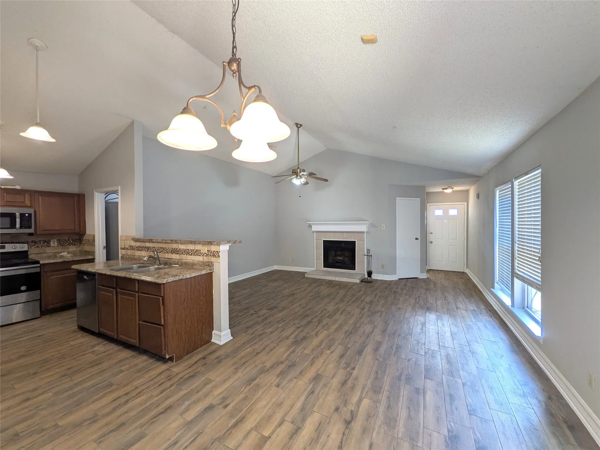 Vaulted ceilings, wood-finish flooring, and a fireplace with a mantel