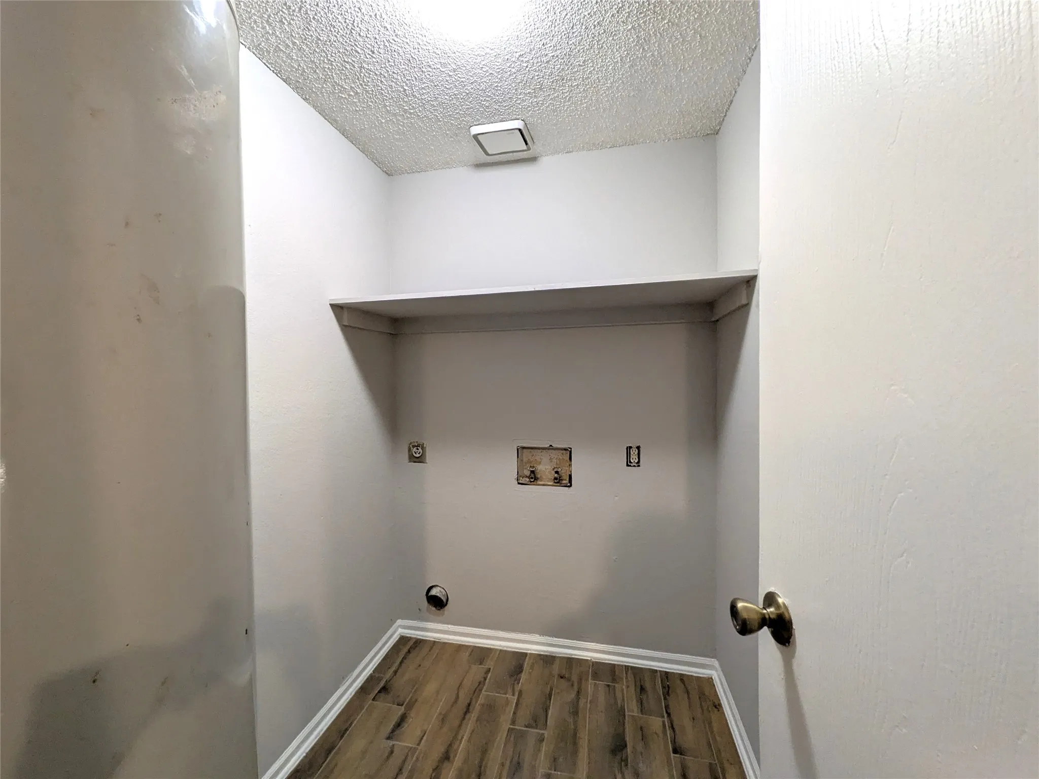 Laundry area with wood-finish flooring, a built-in shelf, and a ceiling-mounted light fixture