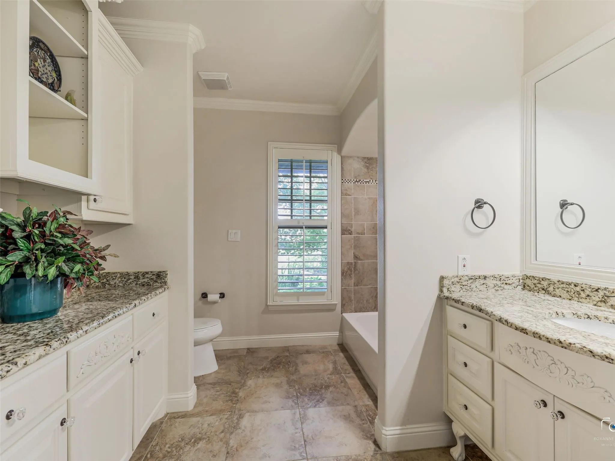 Dual vanity with granite countertops, white cabinetry, and decorative hardware