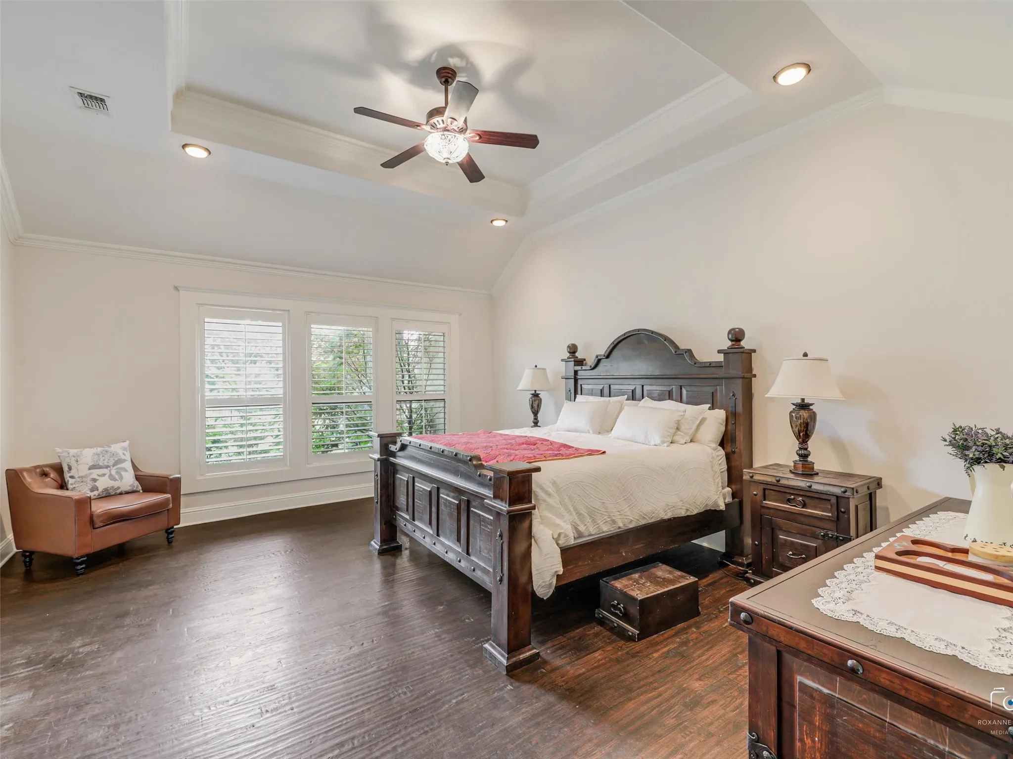 Wood-finish flooring, vaulted ceiling with recessed lighting, ceiling fan, crown molding, and plantation shutters