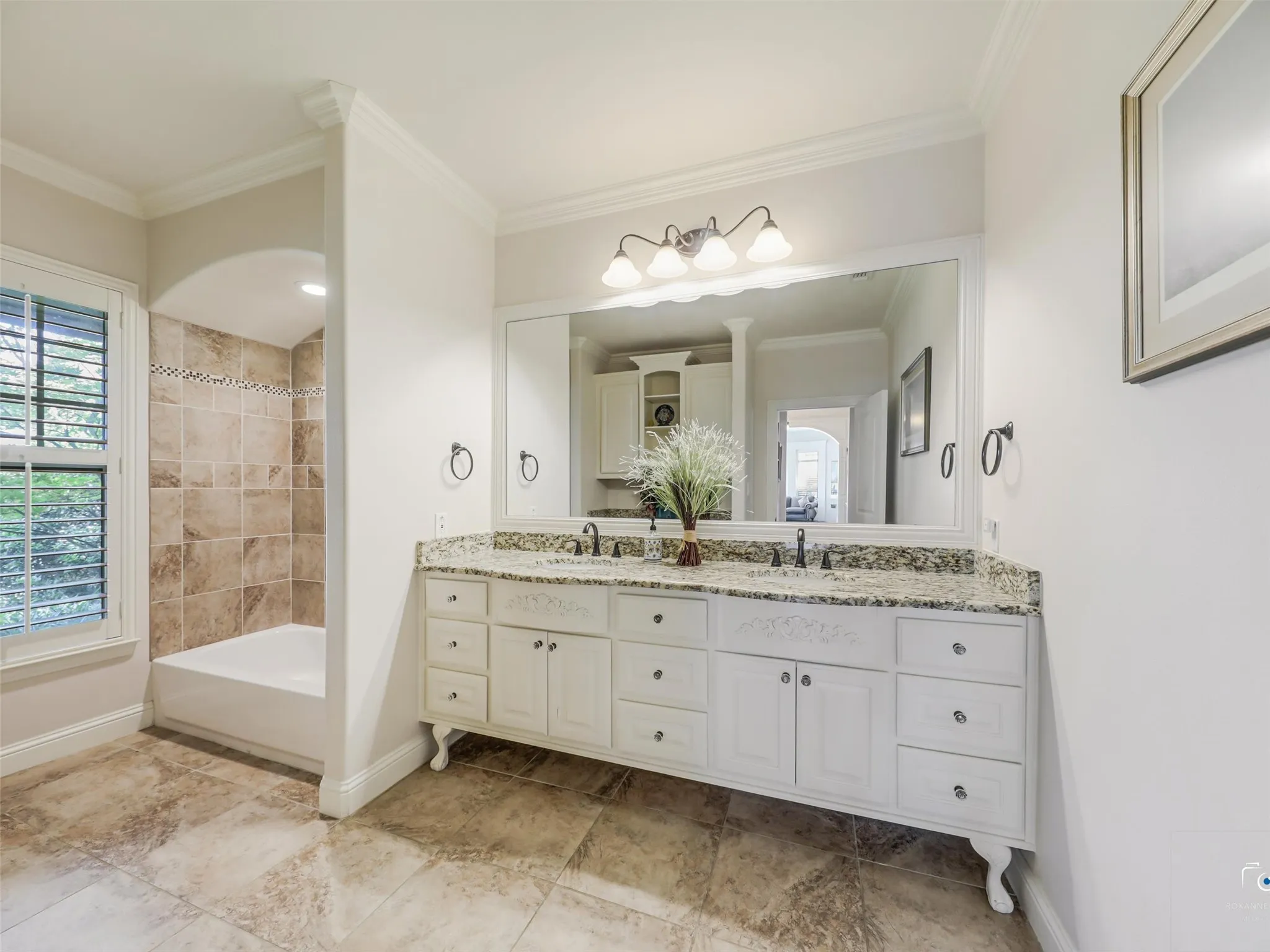 Double vanity with granite countertop, integrated sinks, and ample storage cabinetry