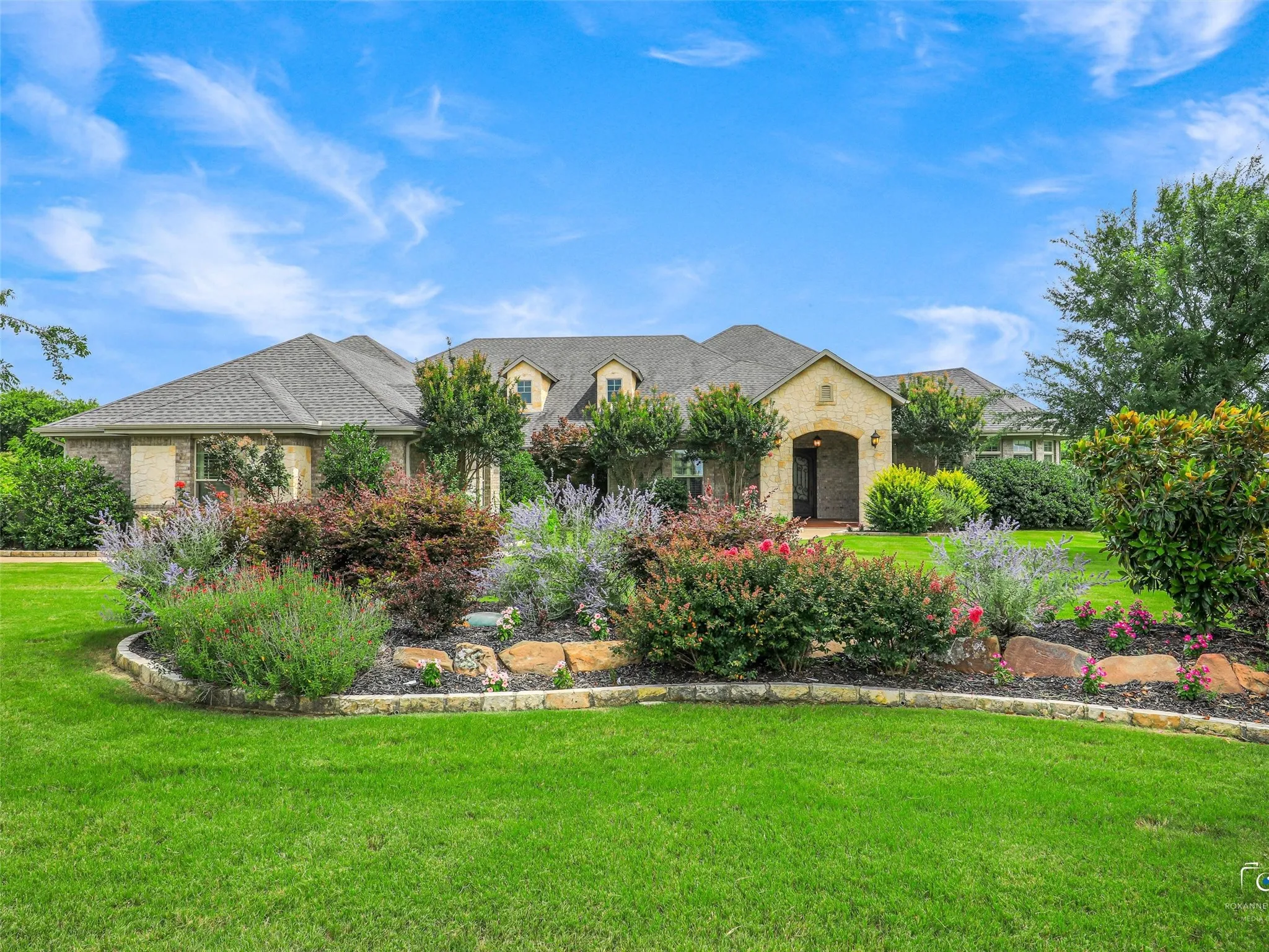 Stone facade residence featuring multiple gables and a covered entry