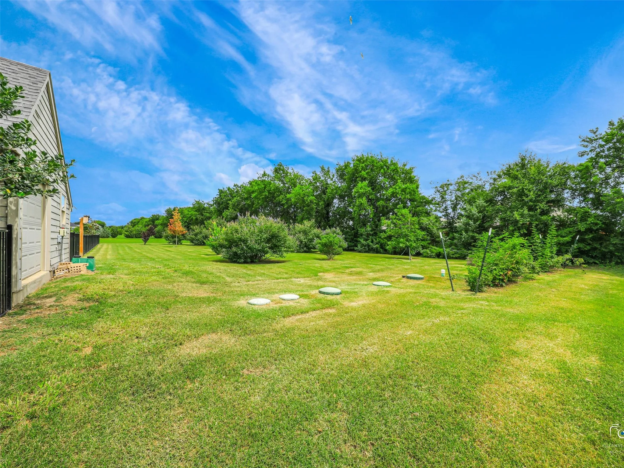Expansive green lawn with mature trees and perimeter fencing