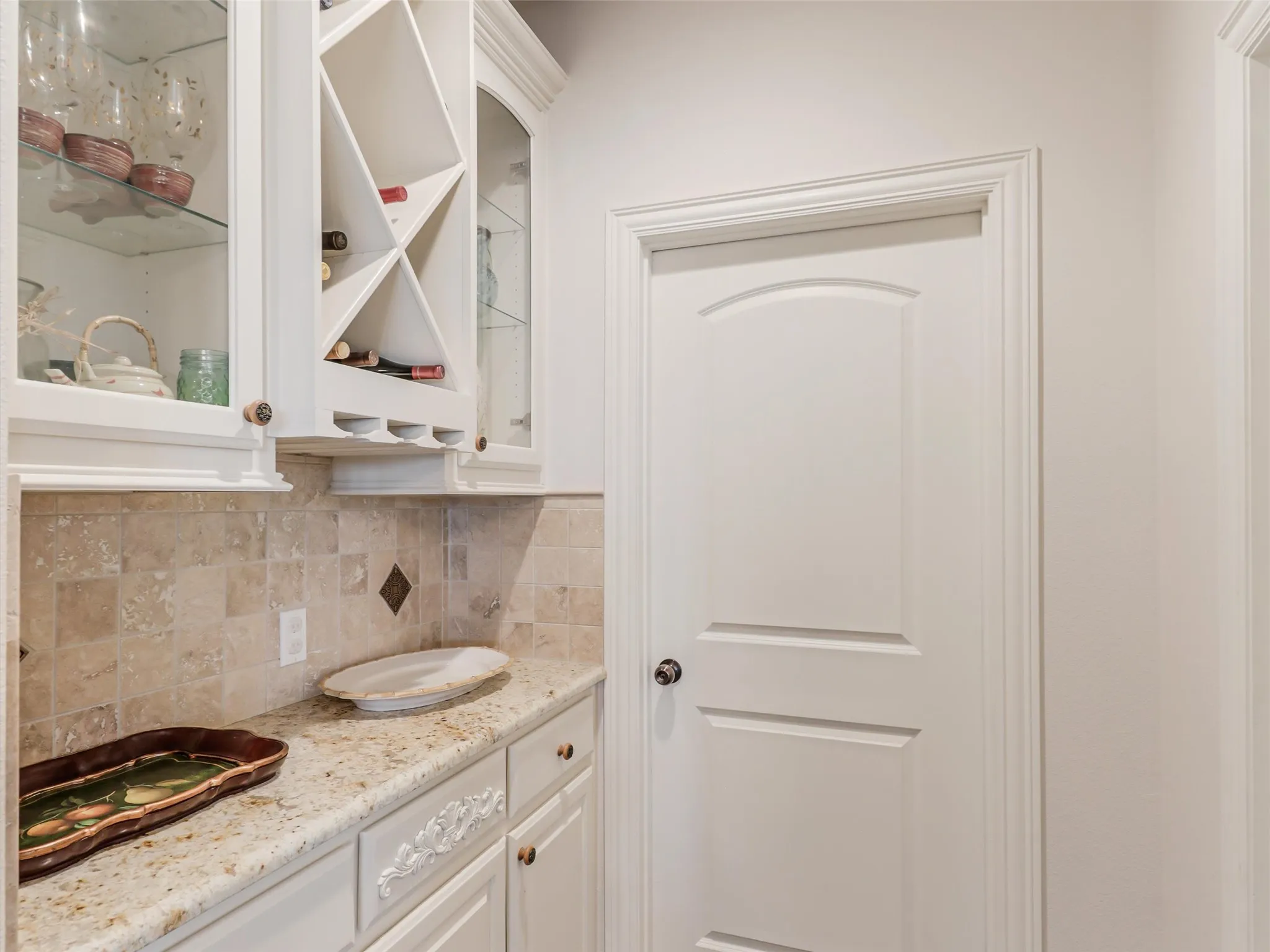 Built-in cabinetry with glass-front uppers, an integrated wine rack, and stemware storage