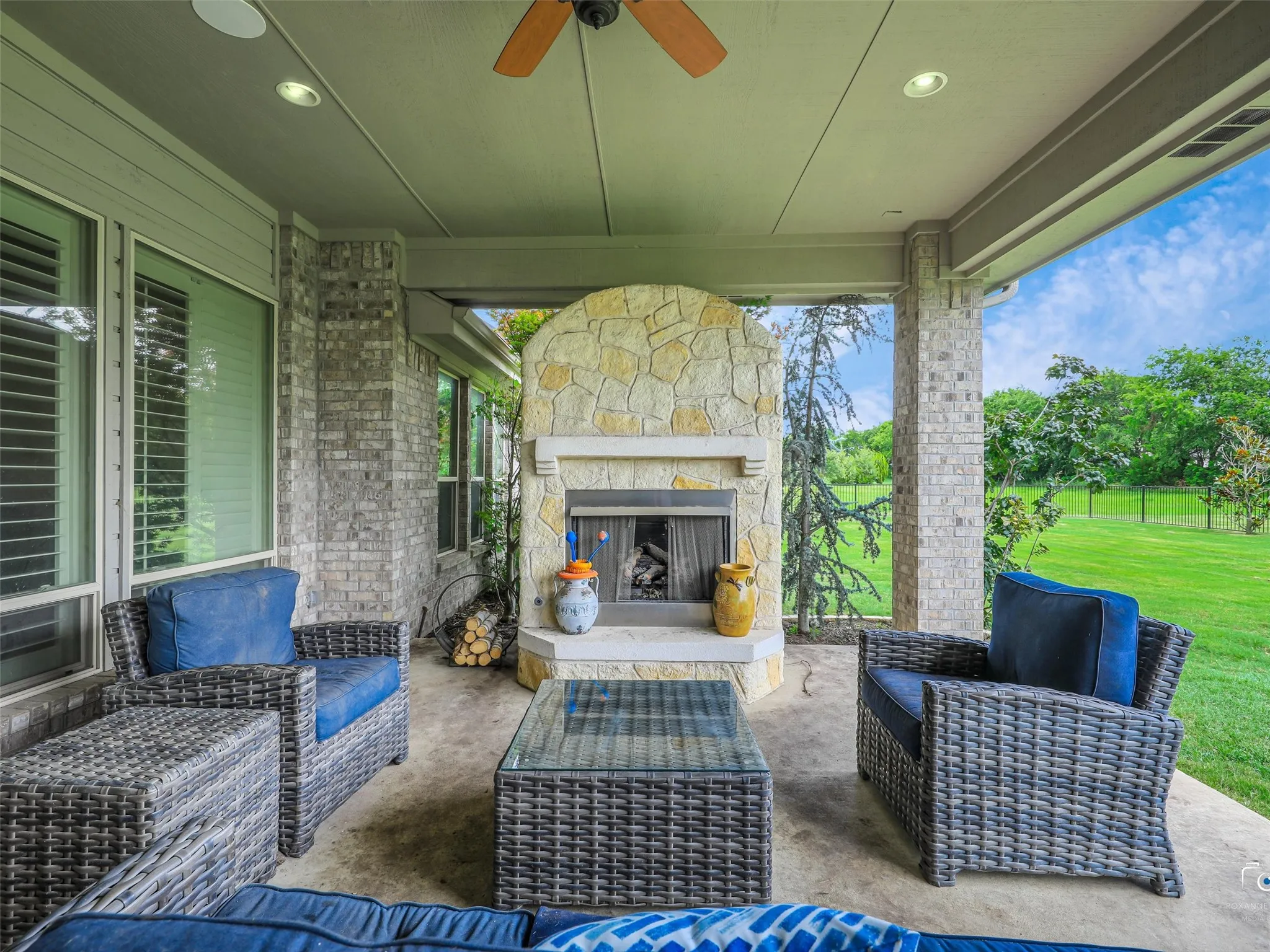 Covered patio featuring a stone-clad fireplace and recessed lighting