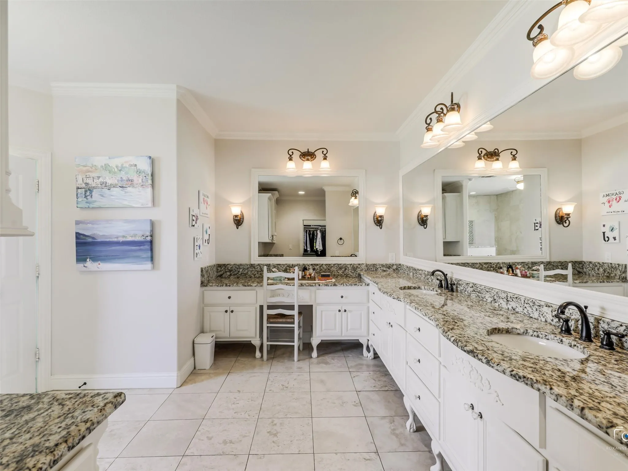 Spacious bathroom featuring two vanity areas, dual sinks, granite countertops, tile flooring, and built-in cabinetry