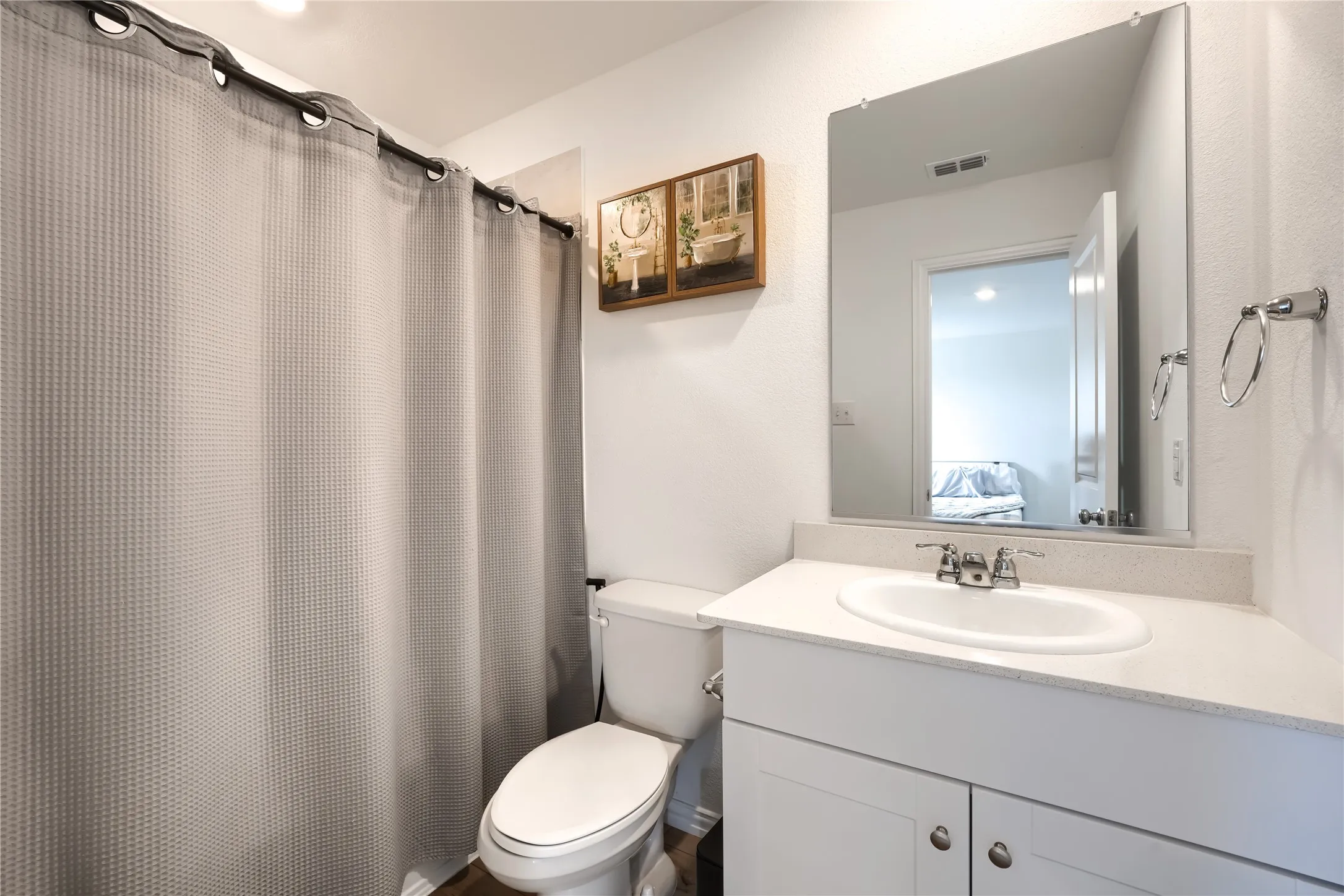 Bathroom featuring a single vanity with an integrated sink, polished chrome faucet, and a wall-mounted mirror