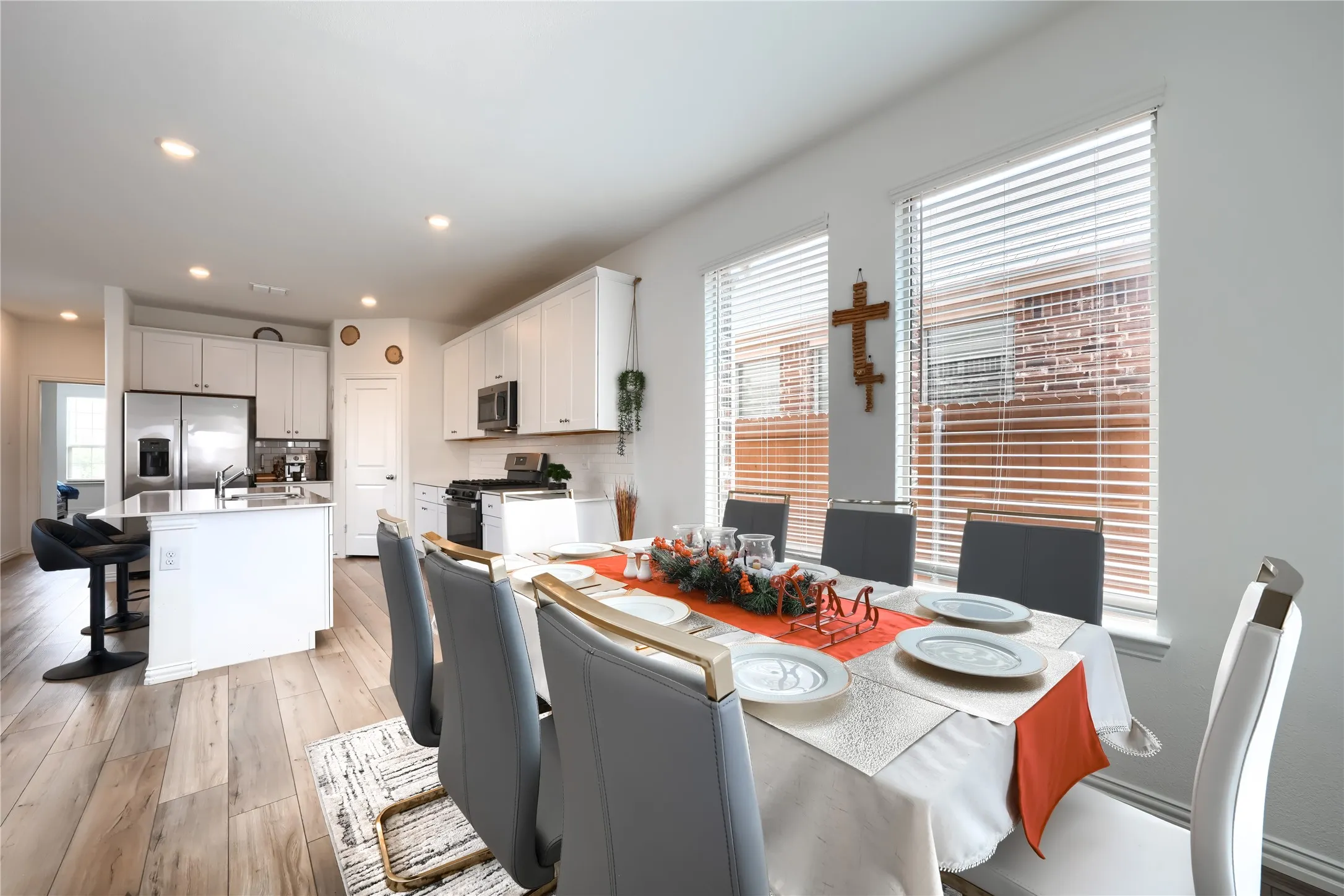 White kitchen cabinetry with stainless steel appliances, a kitchen island with a sink, and wood-finish flooring