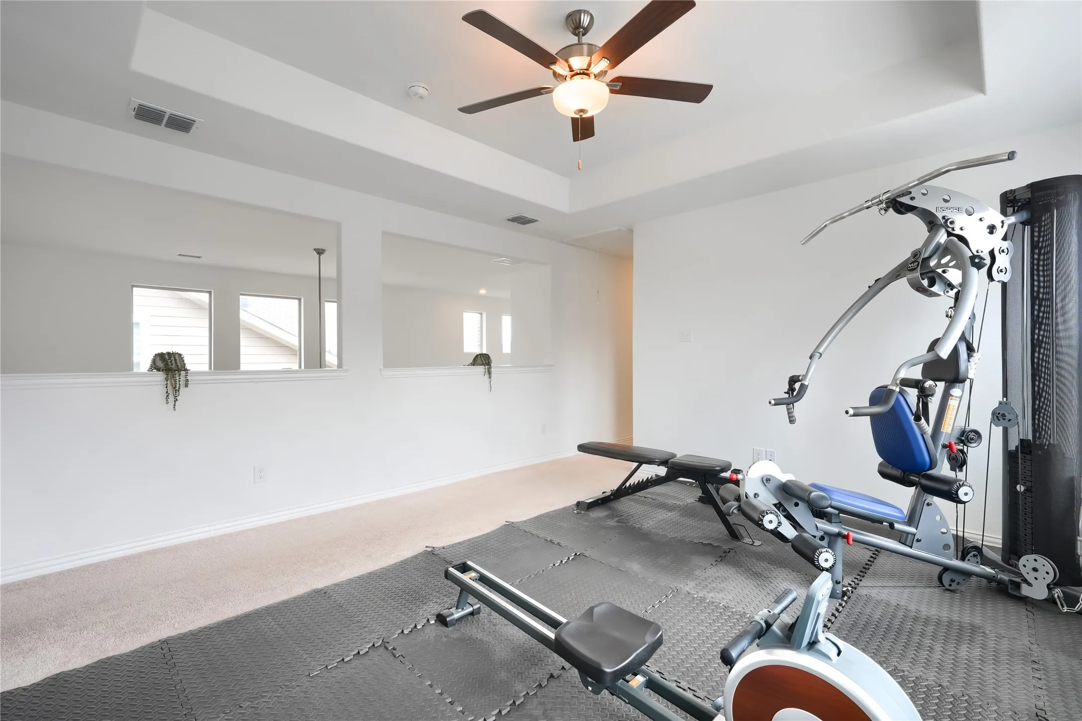 Recessed ceiling with integrated lighting, ceiling fan, carpet flooring, and white painted walls