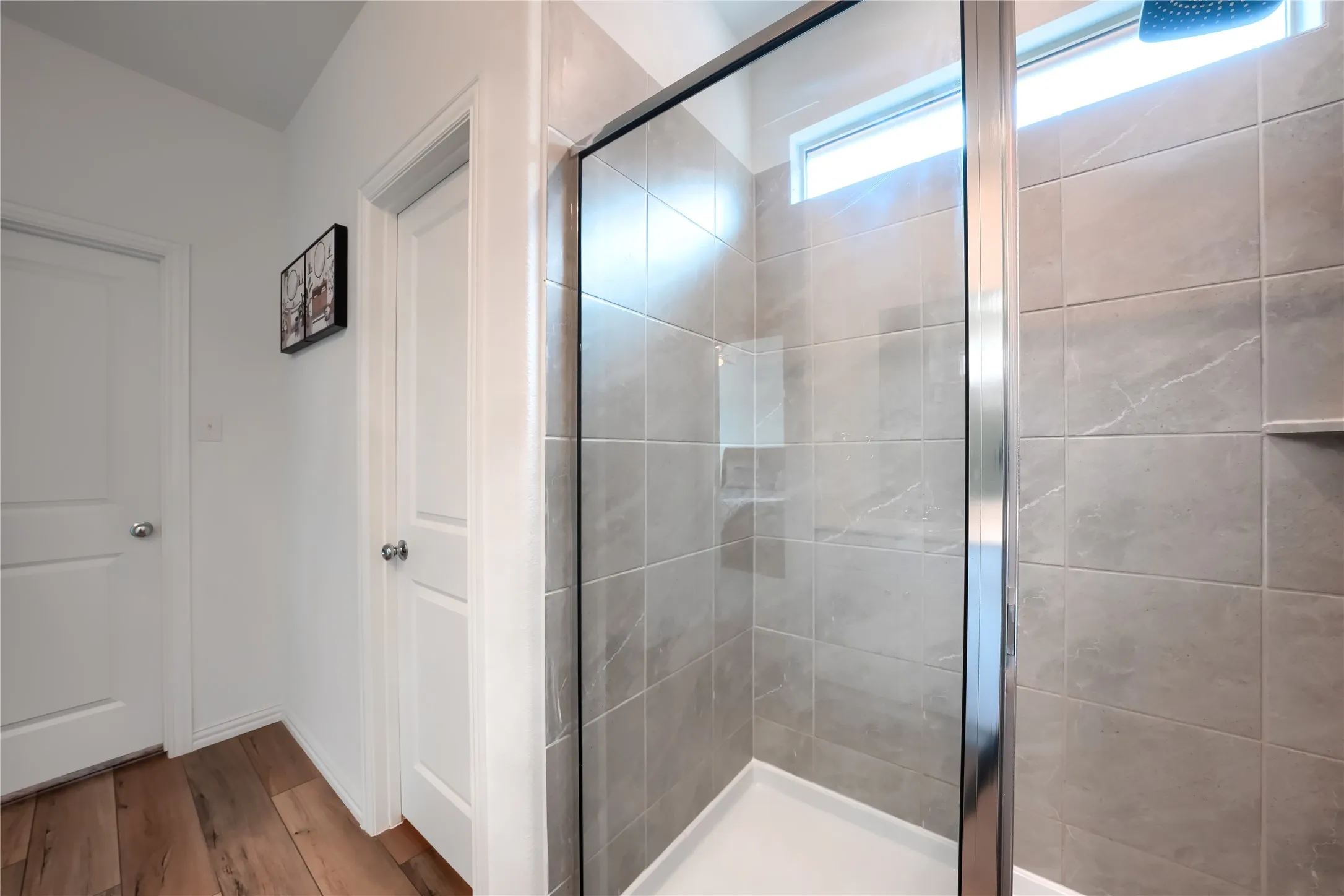 Glass-enclosed shower with a tiled surround, integrated shelf, and transom window