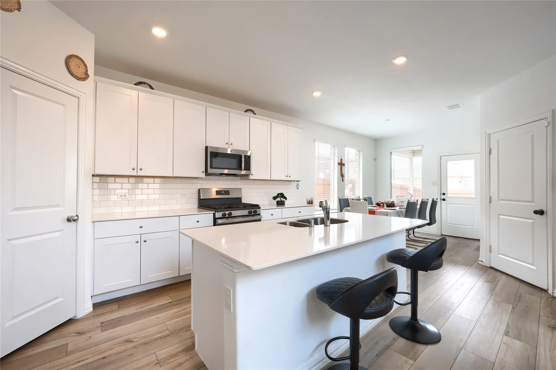 Kitchen featuring a central island, stainless steel appliances, wood-finish flooring, white cabinetry, and white subway tile backsplash