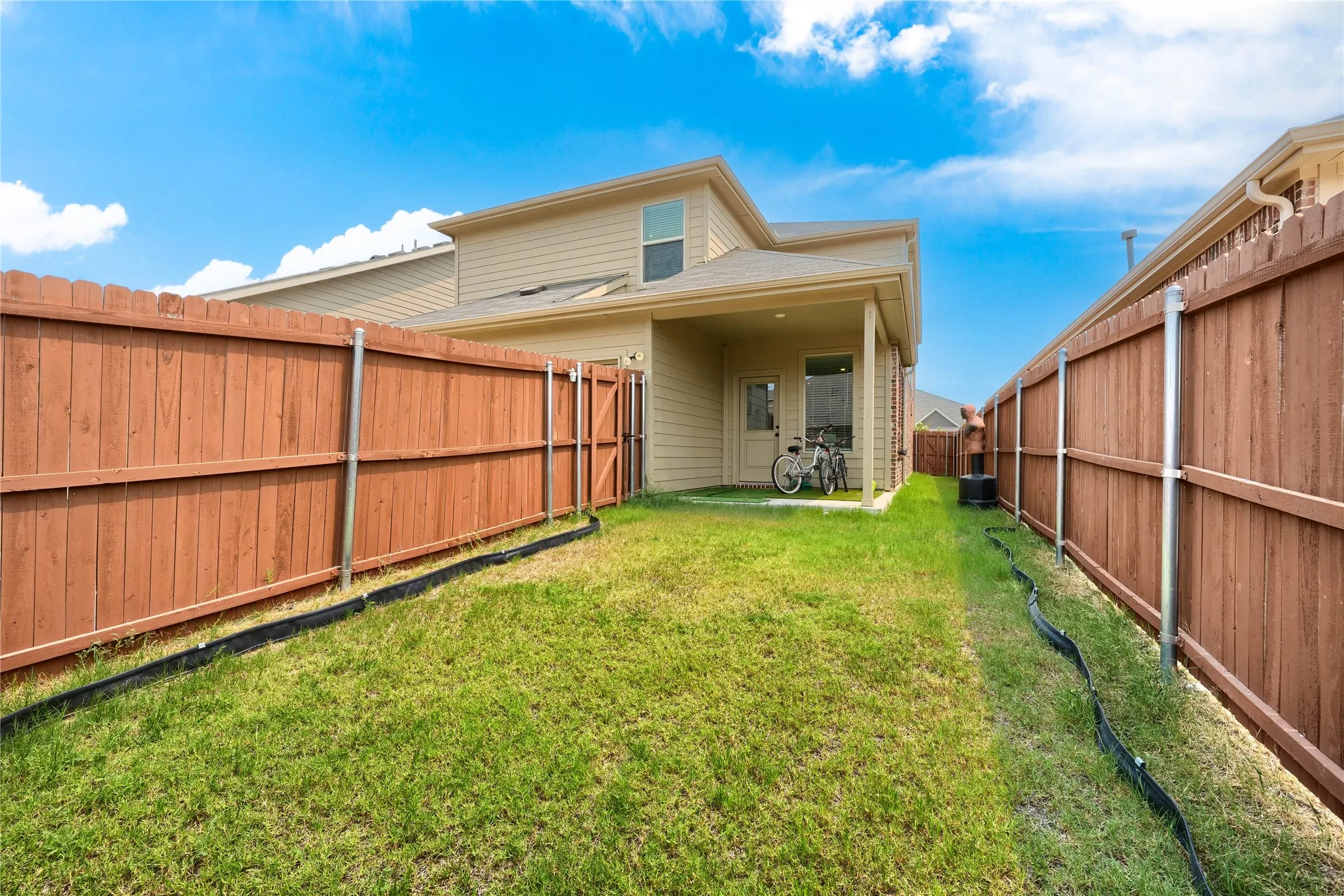 Grassed backyard with wood fencing and a covered patio area