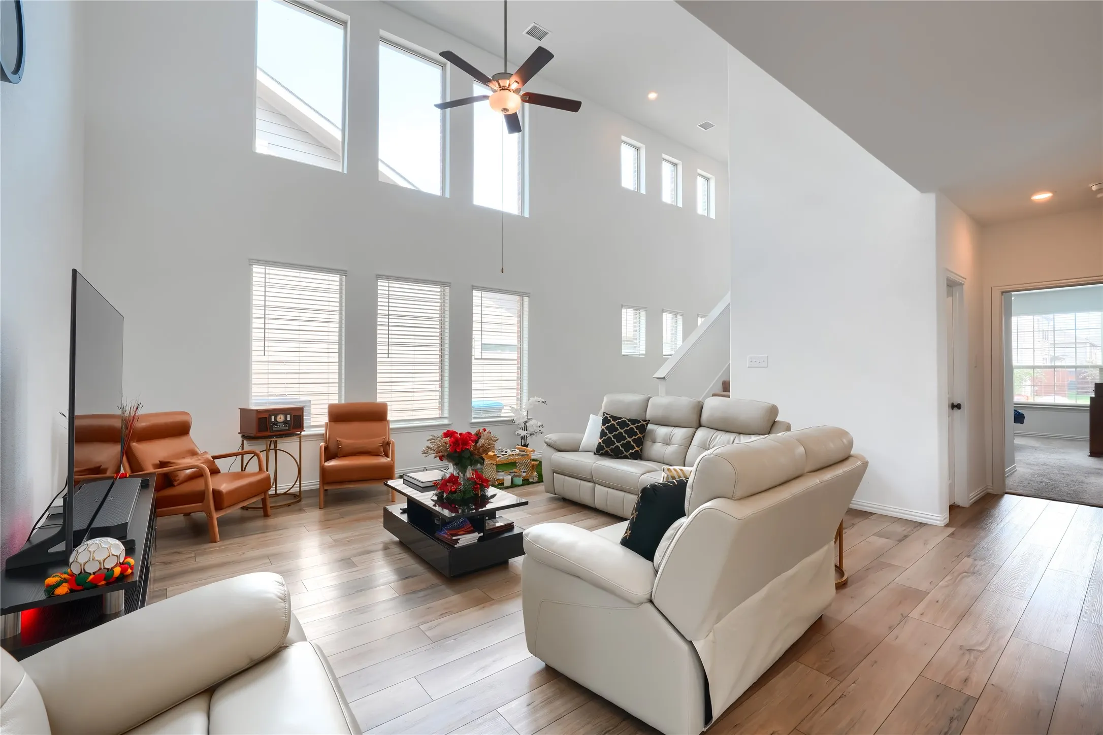 Vaulted ceilings, wood-finish flooring, recessed lighting, ceiling fan, and multiple windows with blinds