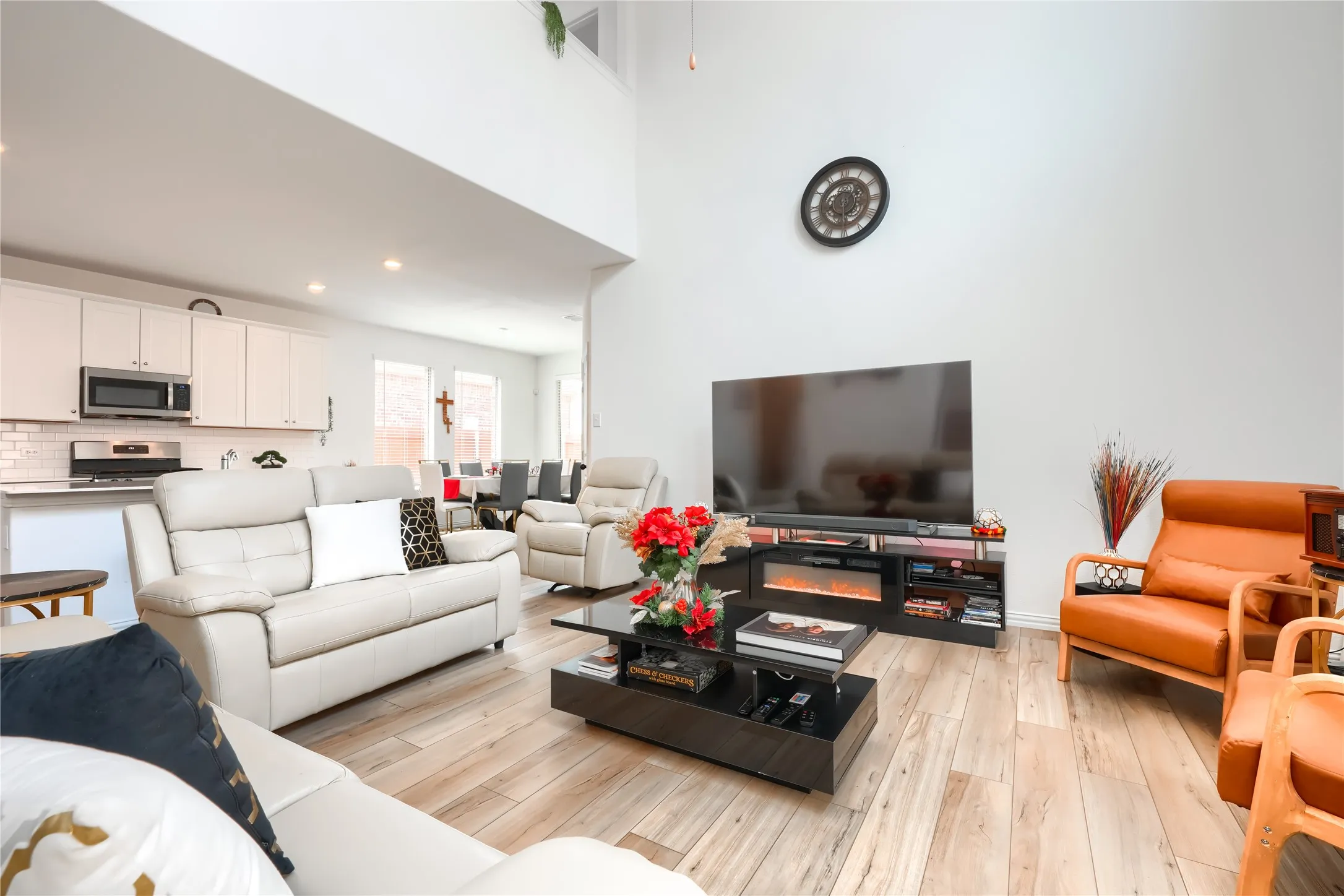 High ceilings, wood-finish flooring, recessed lighting, white cabinetry, and stainless steel appliances