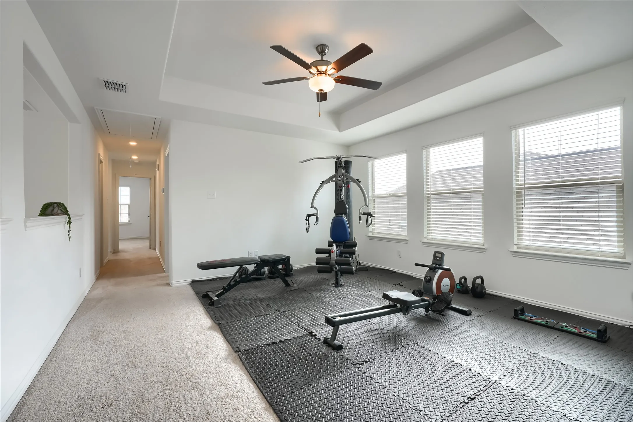 Tray ceiling with a ceiling fan, recessed lighting, multiple windows with blinds, and carpeted flooring