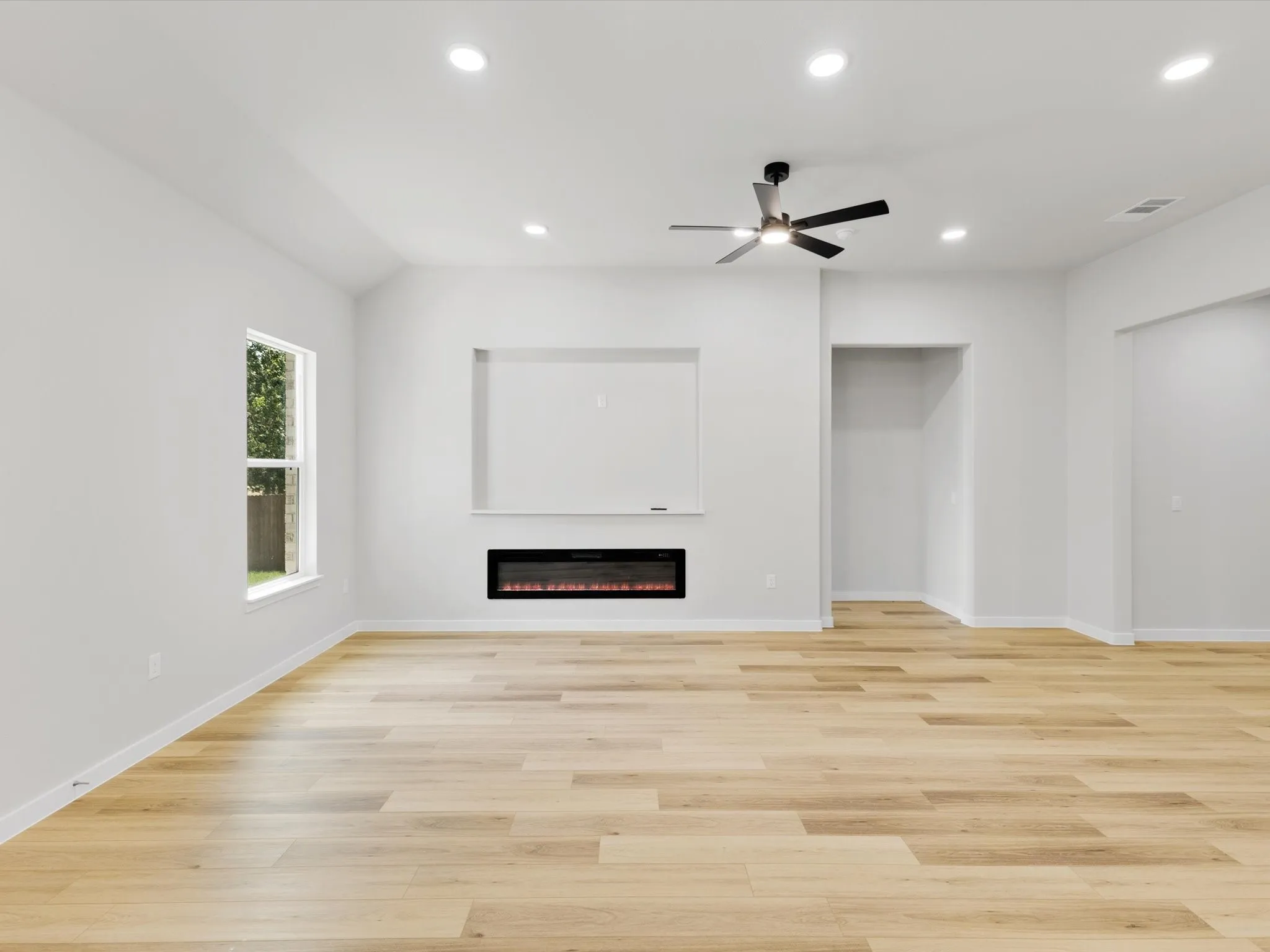 Spacious room featuring wood-finish flooring, recessed lighting, and an electric fireplace with a built-in media niche