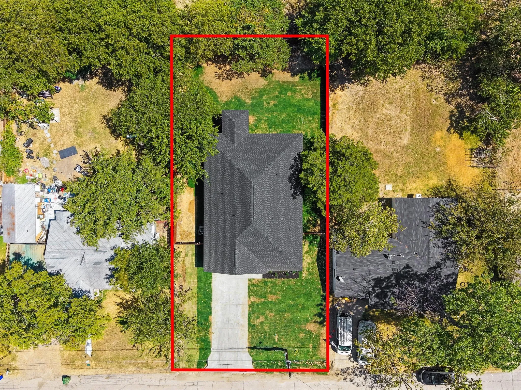 Property featuring a dark shingle roof, a paved driveway, and a grass lawn