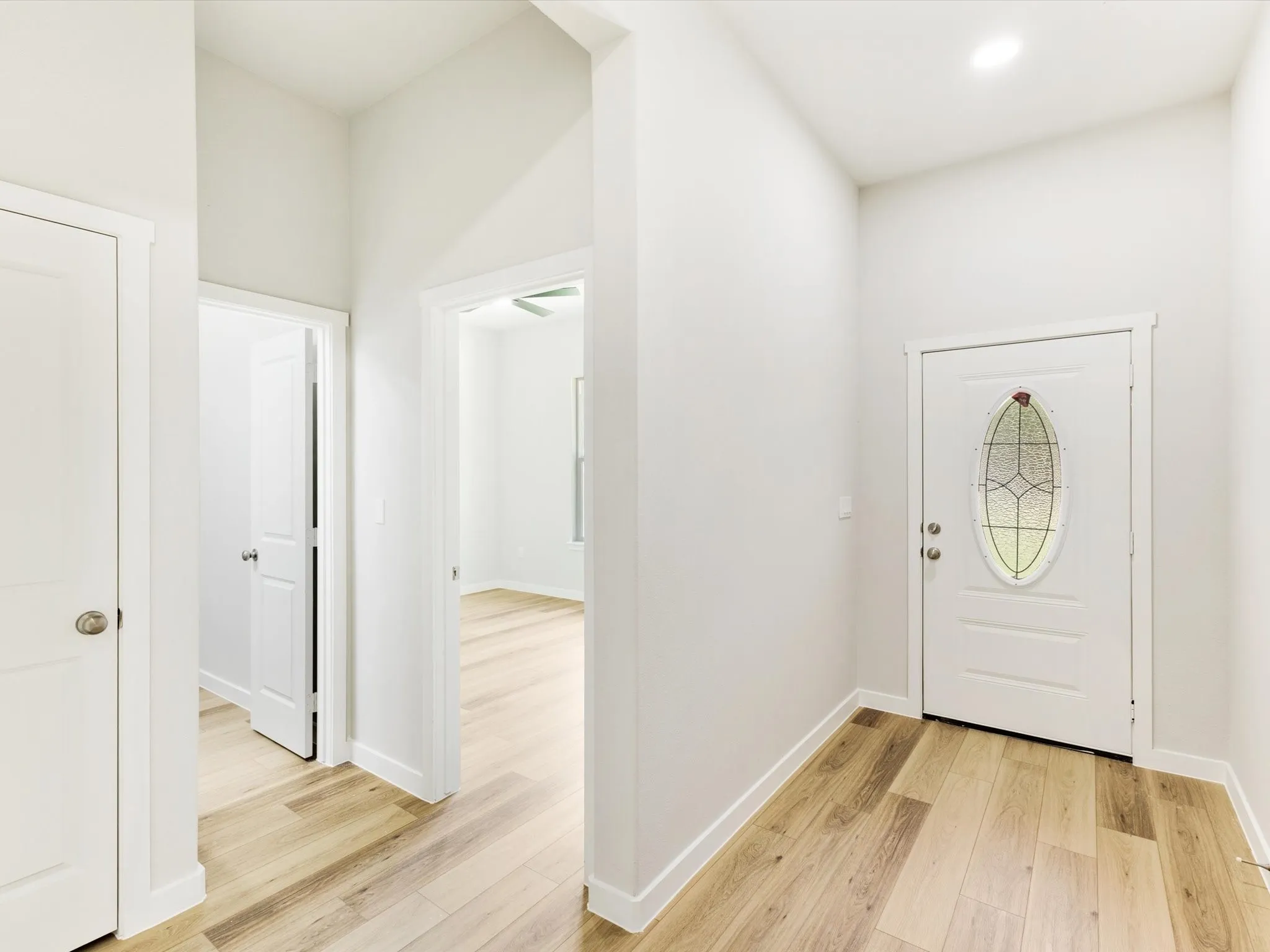 Entryway with wood-finish flooring, recessed lighting, and a white door with decorative glass inlay