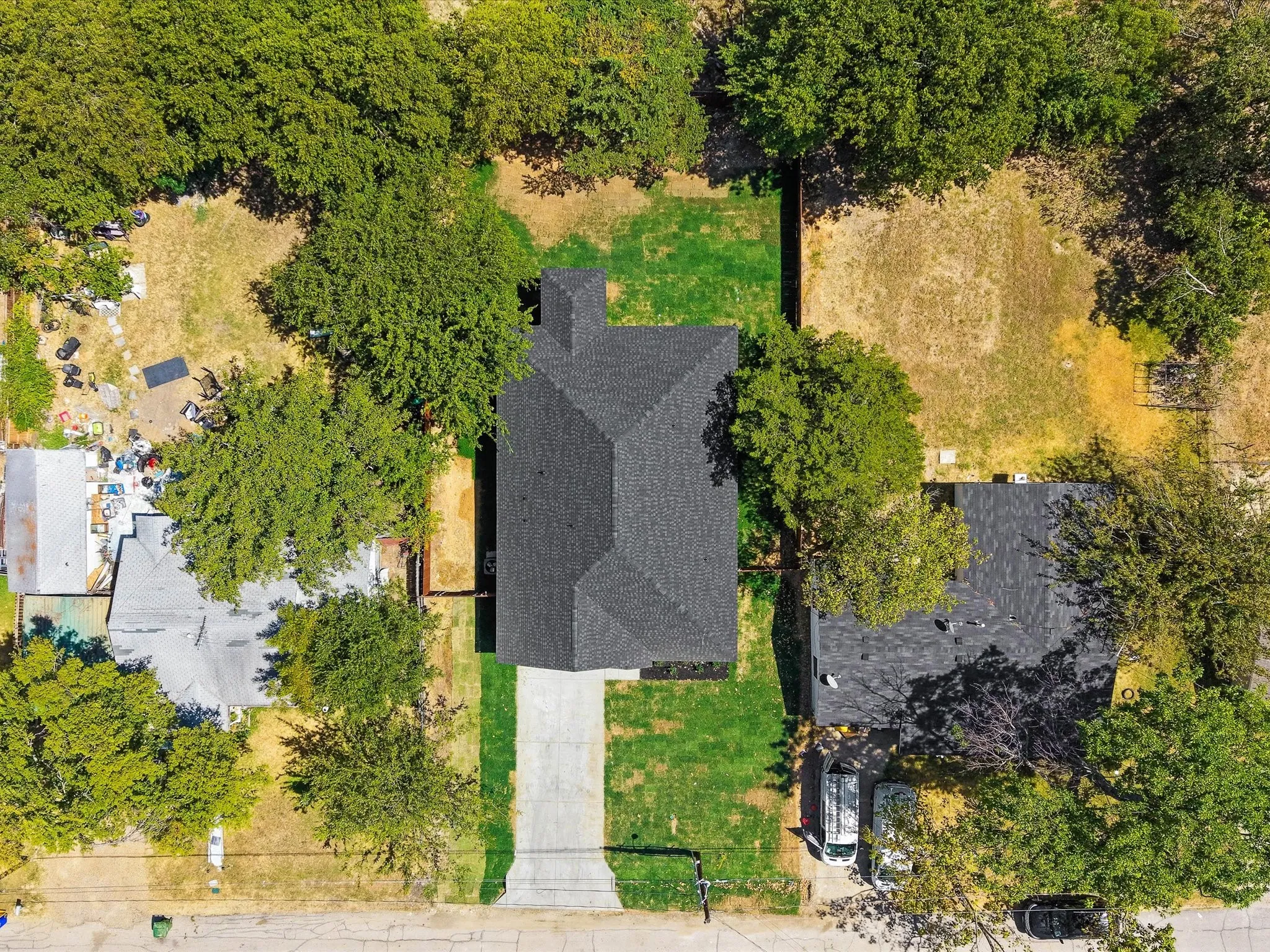 Dark-shingle roof, extensive green lawn, and mature trees