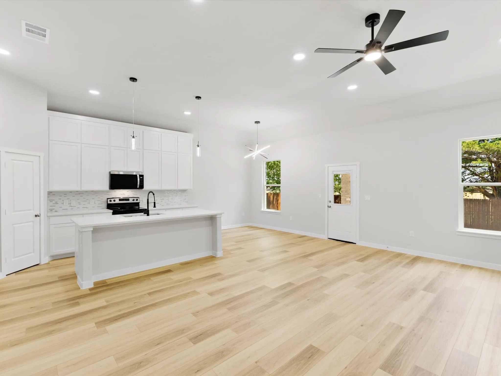 Open-concept living space featuring wood-finish flooring, recessed lighting, and a contemporary ceiling fan