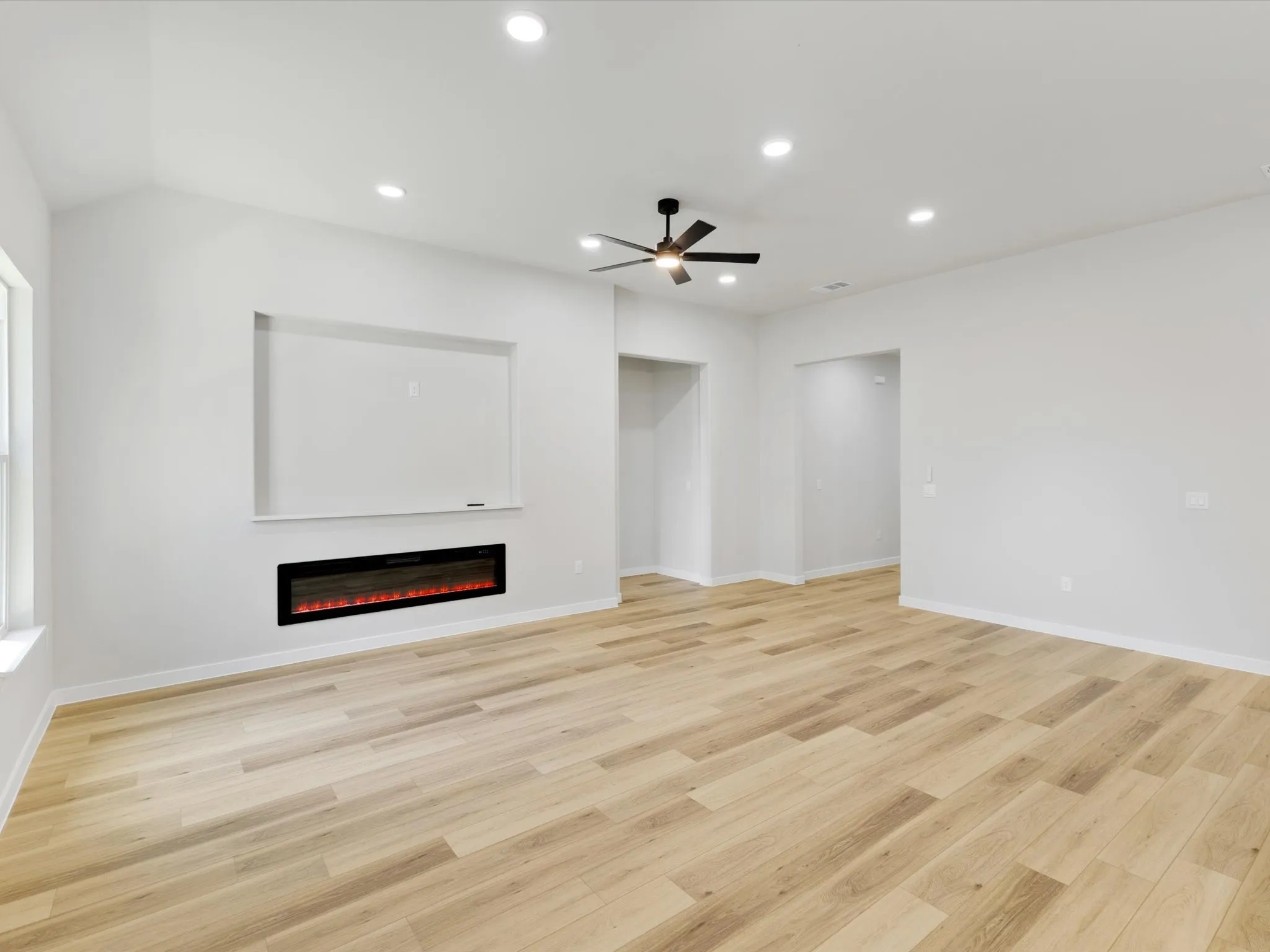 Recessed lighting, wood-finish flooring, ceiling fan, electric fireplace, and vaulted ceiling