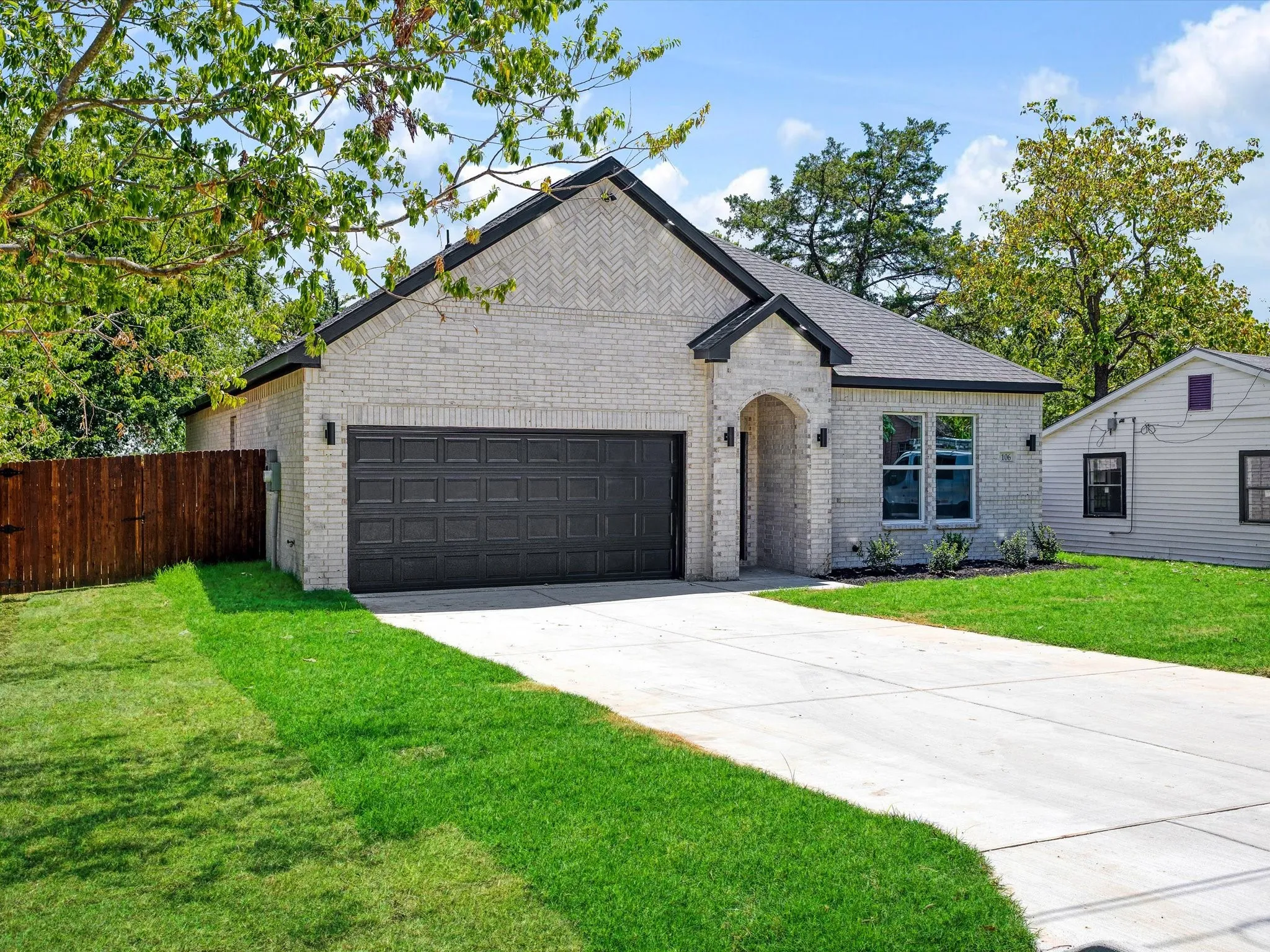 Light brick facade with dark trim, an integrated two-car garage, and an arched entryway
