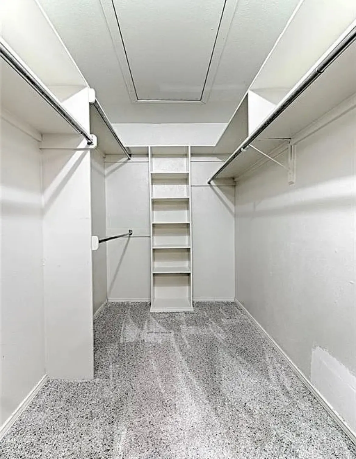 Organized closet featuring a built-in shelving unit, multiple hanging rods, and light-colored carpet flooring