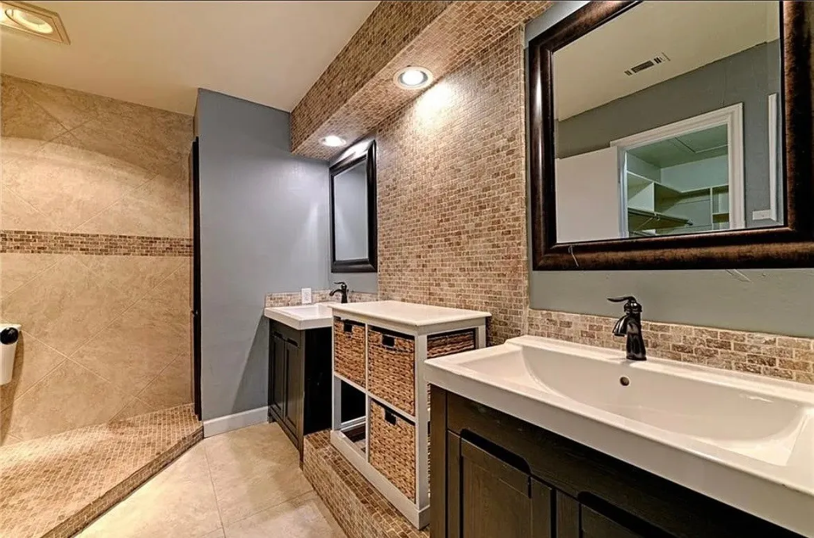 Dual vanity sinks with dark wood cabinetry, a mosaic tile backsplash, and recessed lighting