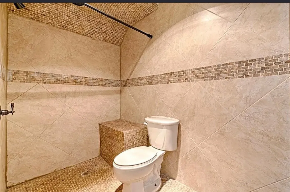 Walk-in shower with full-height large format wall tile, mosaic accent band, and mosaic-tiled ceiling
