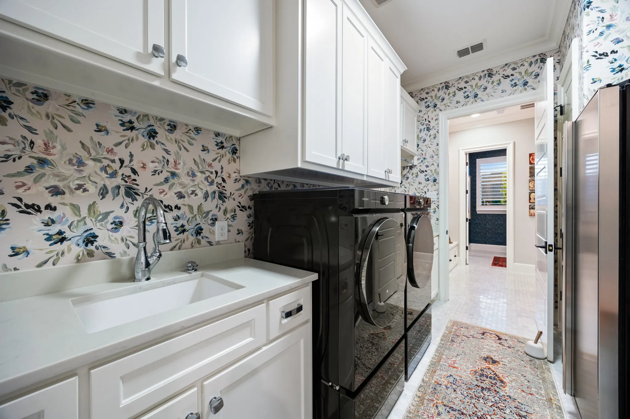 Laundry room finished with patterned tile and rich cabinetry, as stylish as the rest of the home.